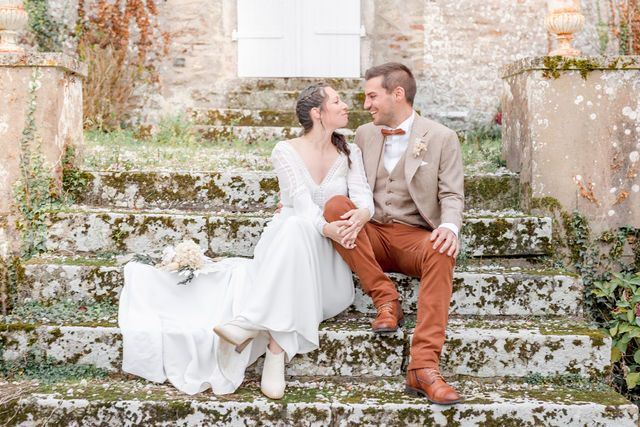 Romantic moment on ancient stone steps with white dress and rust-colored details at French chateau.