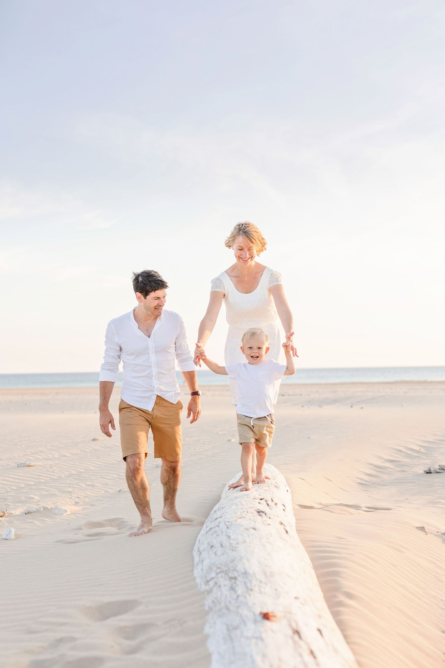 Family walks together along sandy beach dunes in dreamy evening light.