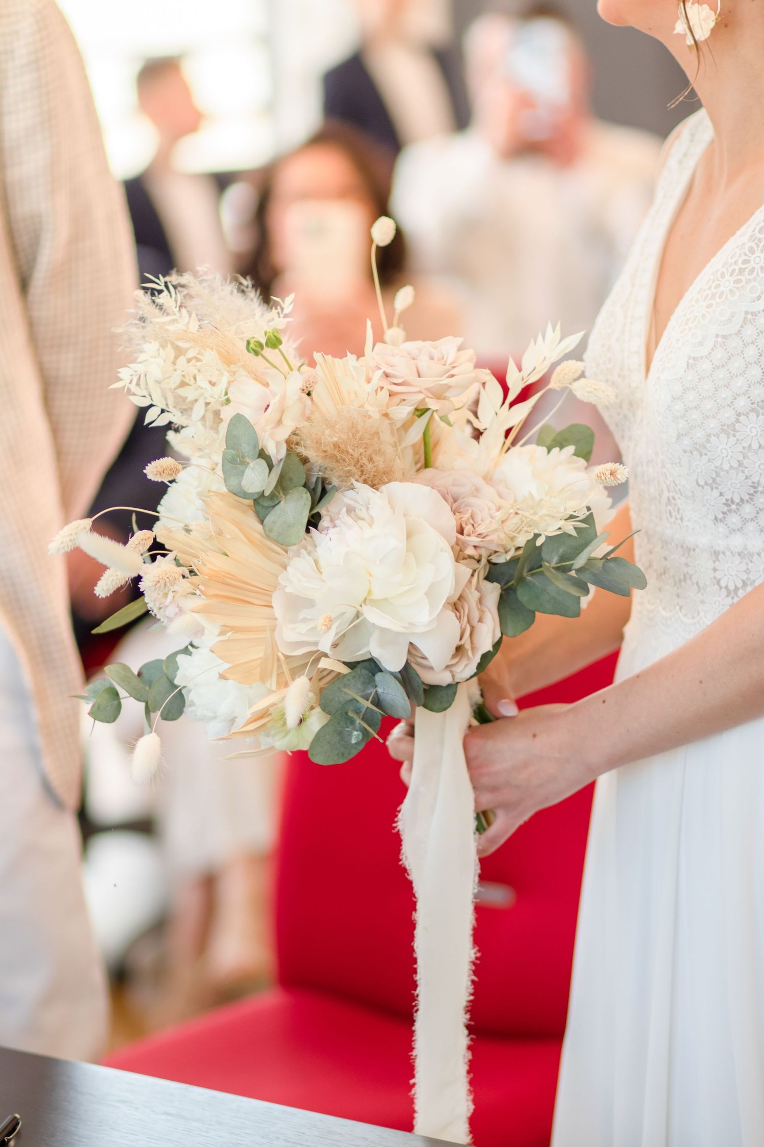 Beautiful white and cream floral bouquets with eucalyptus and ribbons lined up at a wedding.