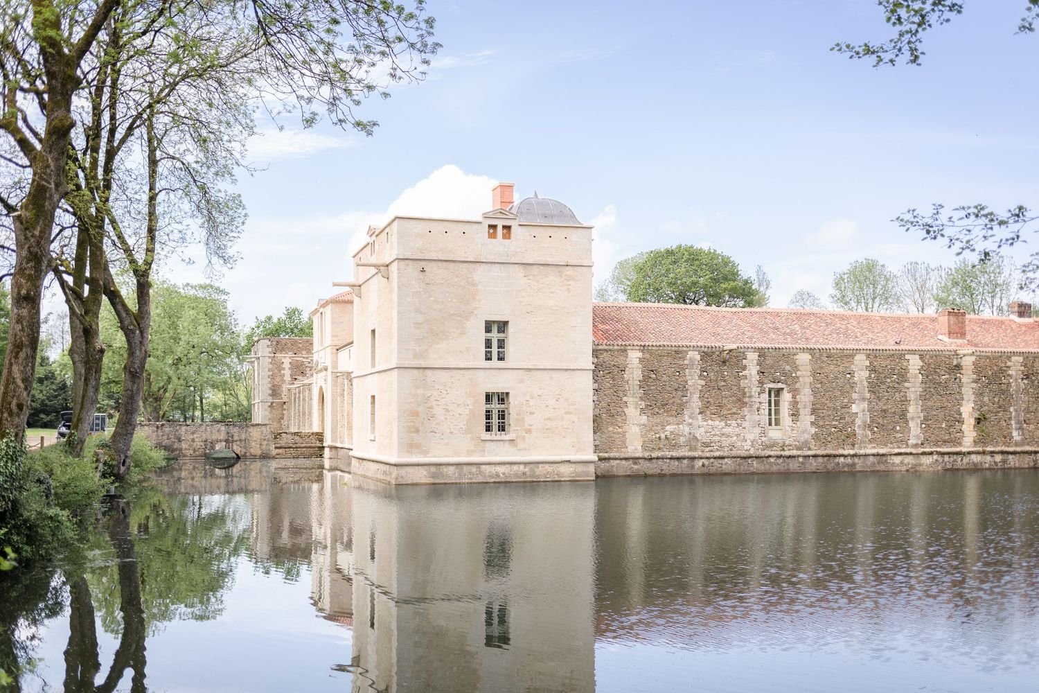 Historic castle with stone walls reflects perfectly in still moat waters.