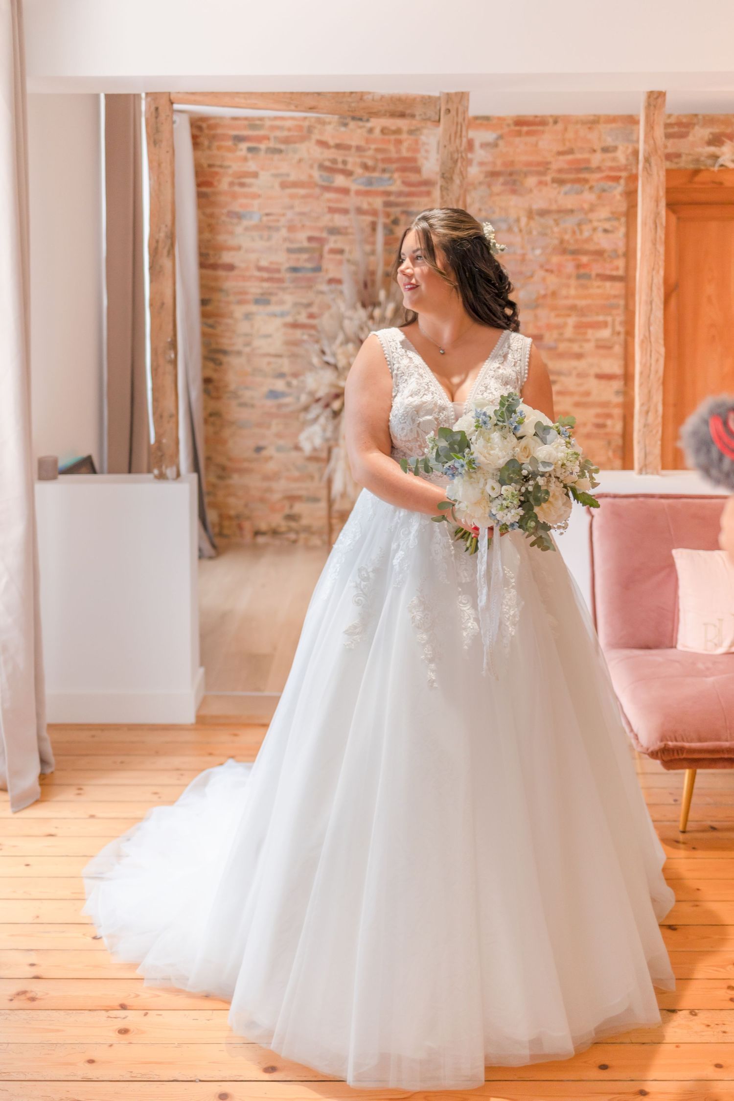 A wedding dress displayed in an elegant indoor setting with exposed brick walls and hardwood floors.