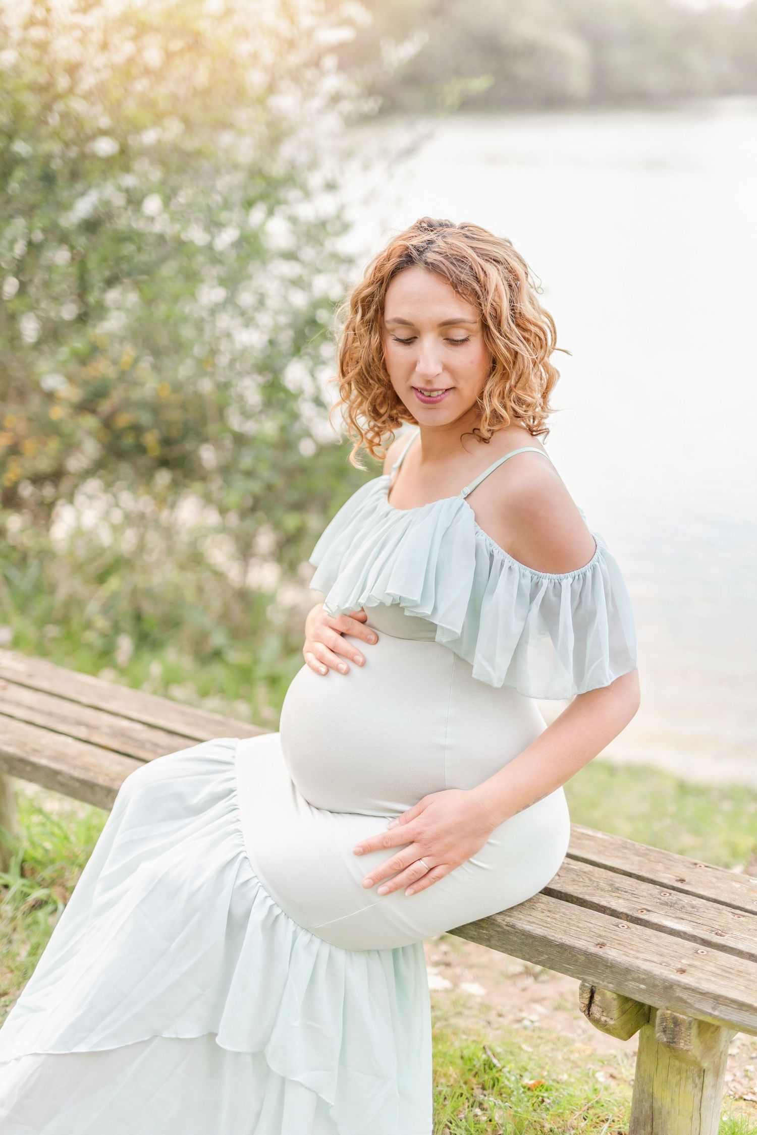 Gentle maternity portraits showing tender moments in soft light by the water.