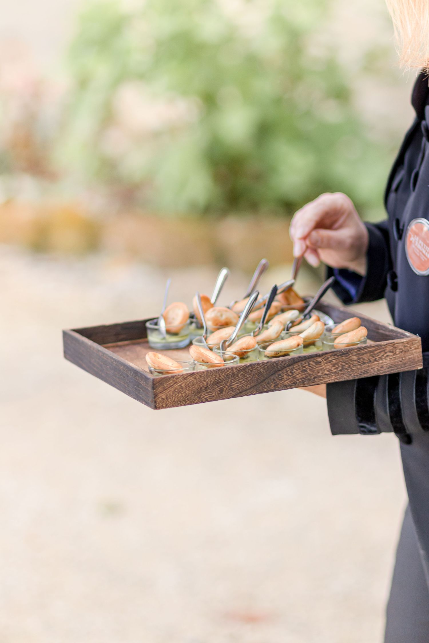 Wooden tray filled with assorted appetizers and hors d'oeuvres being carried at an event.
