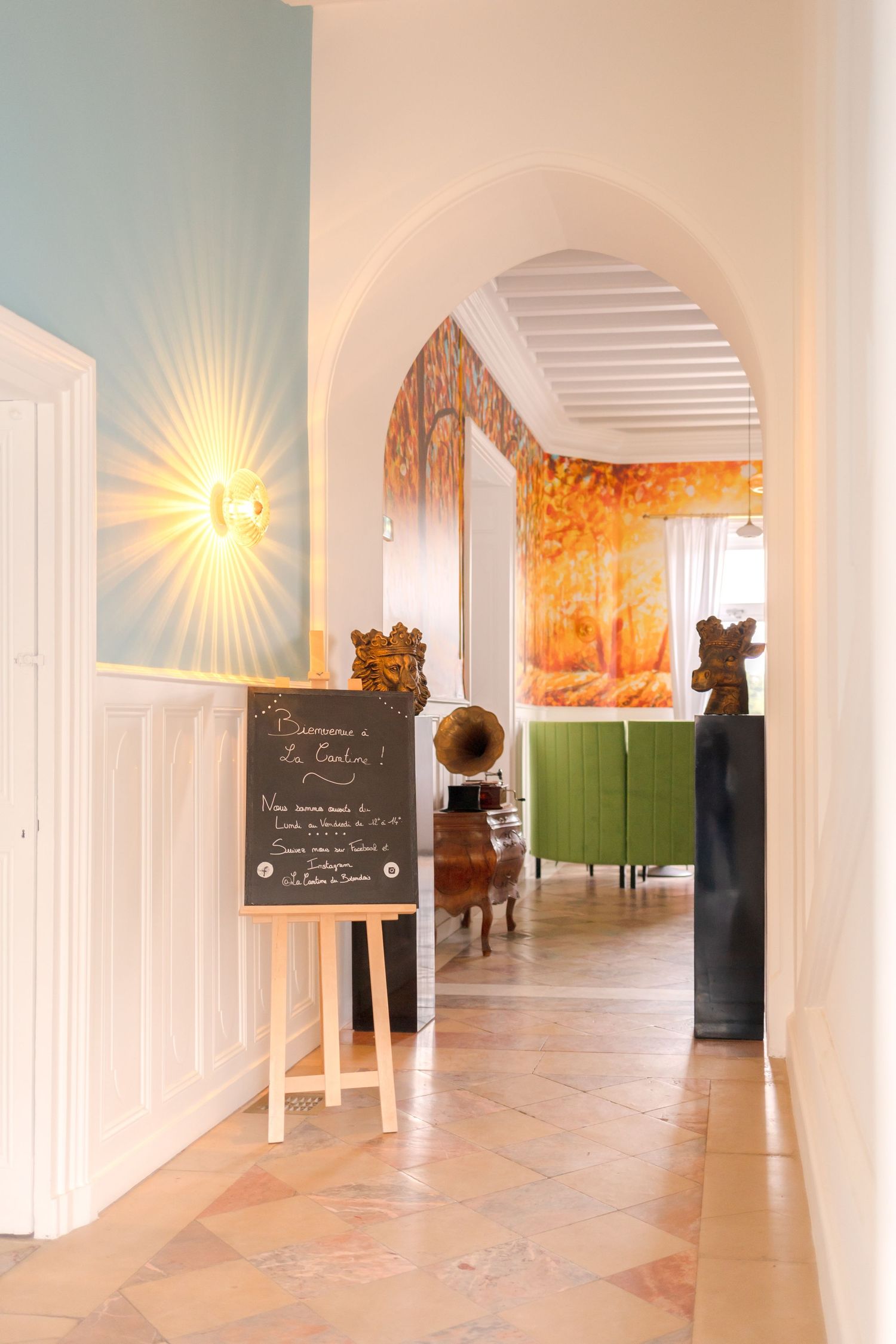 Elegant hallway with arched doorway, chalkboard sign and warm lighting.