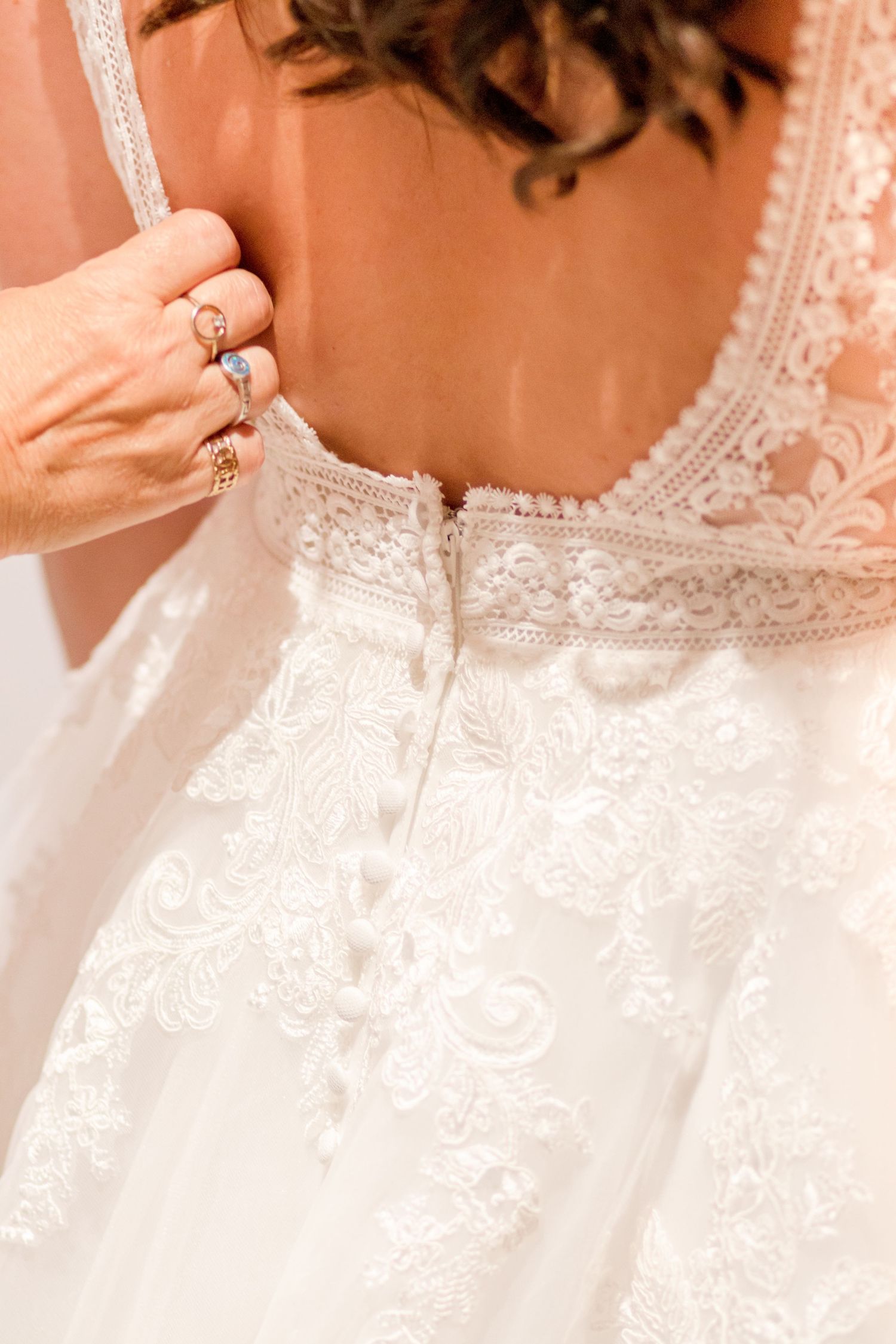 Delicate white lace detail on the back of a wedding gown with intricate embroidery patterns.