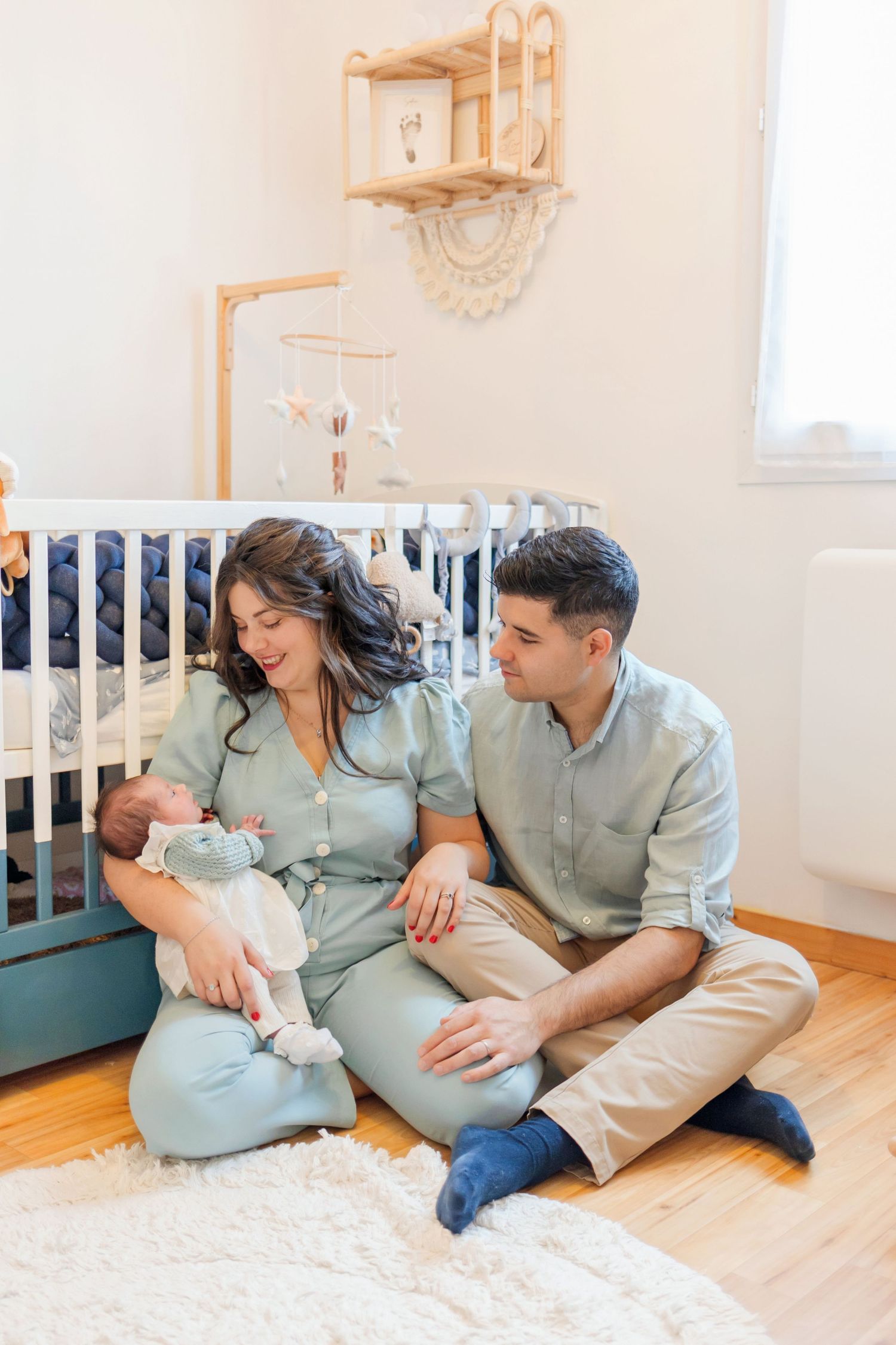 A quiet family moment in a minimalist nursery with wooden accents and white walls.