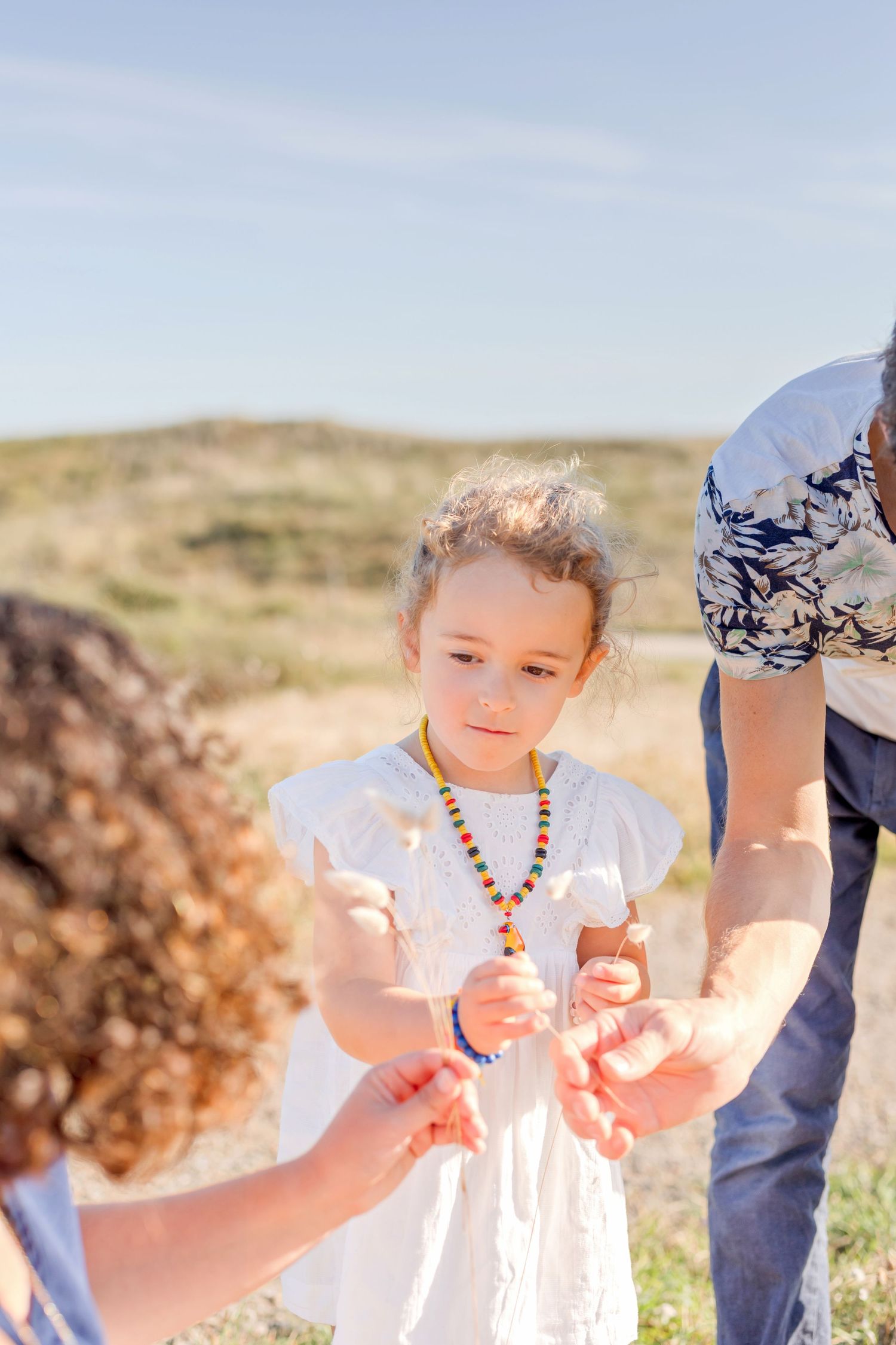 Candid outdoor family interaction on a sunny day with hills in background.