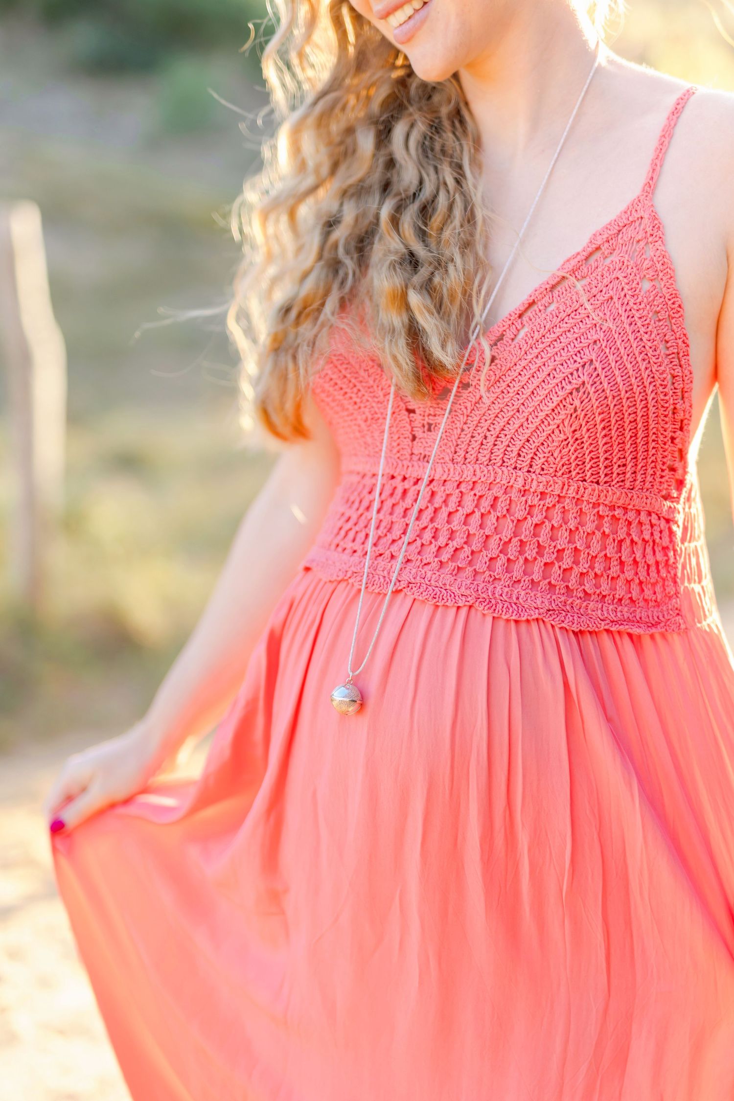 Details of a coral crochet-top sundress photographed in warm evening light.