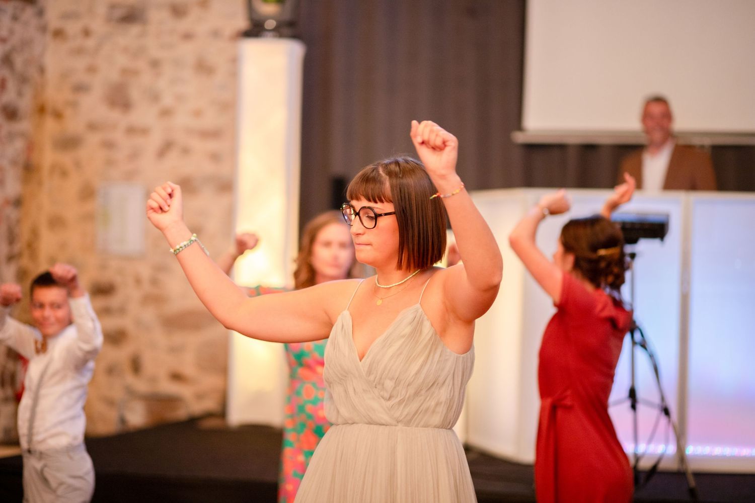 Energetic dance scene at a wedding reception with guests dancing in a rustic venue.