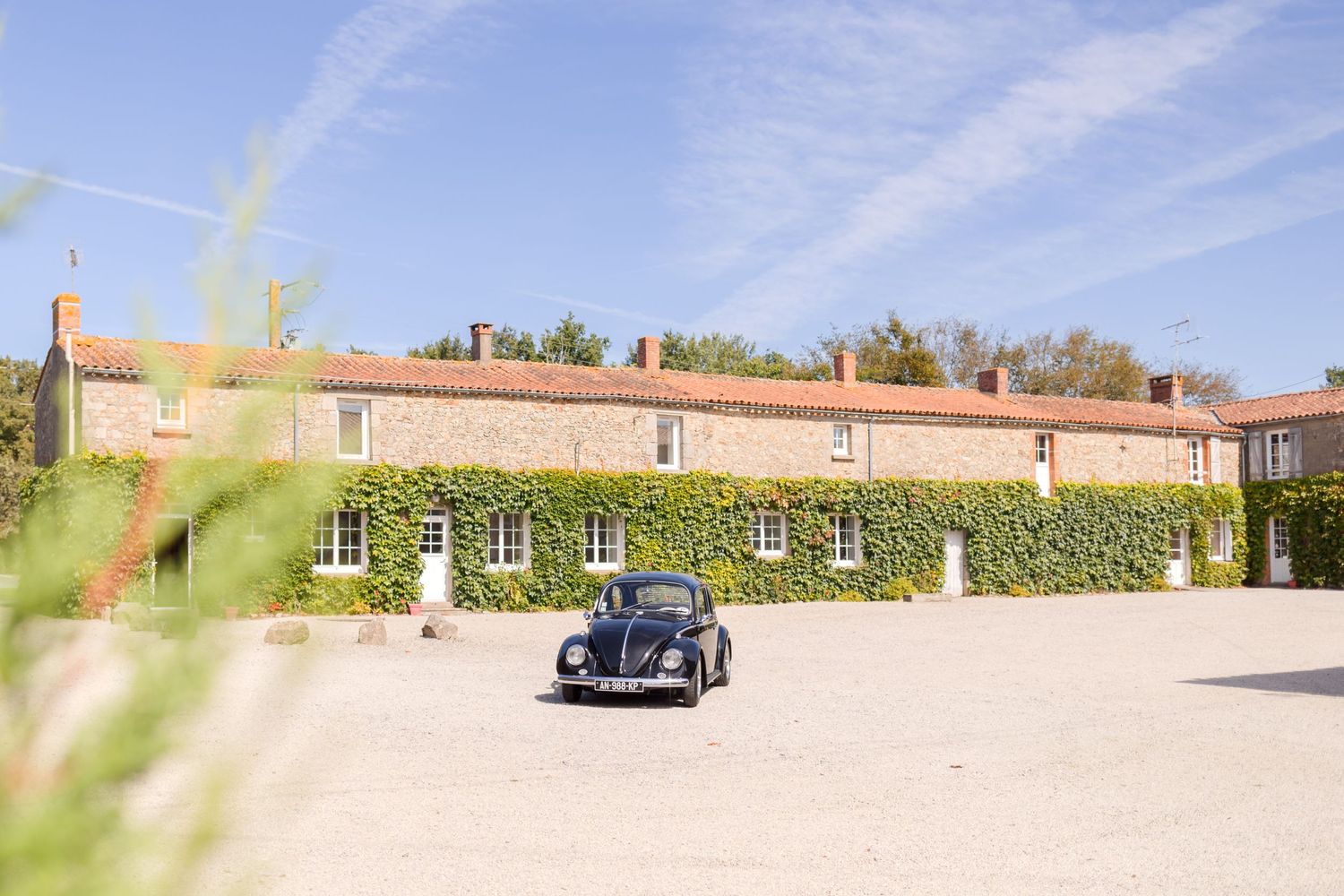 Vintage blue car parked in front of an ivy-covered villa with terracotta roof tiles.