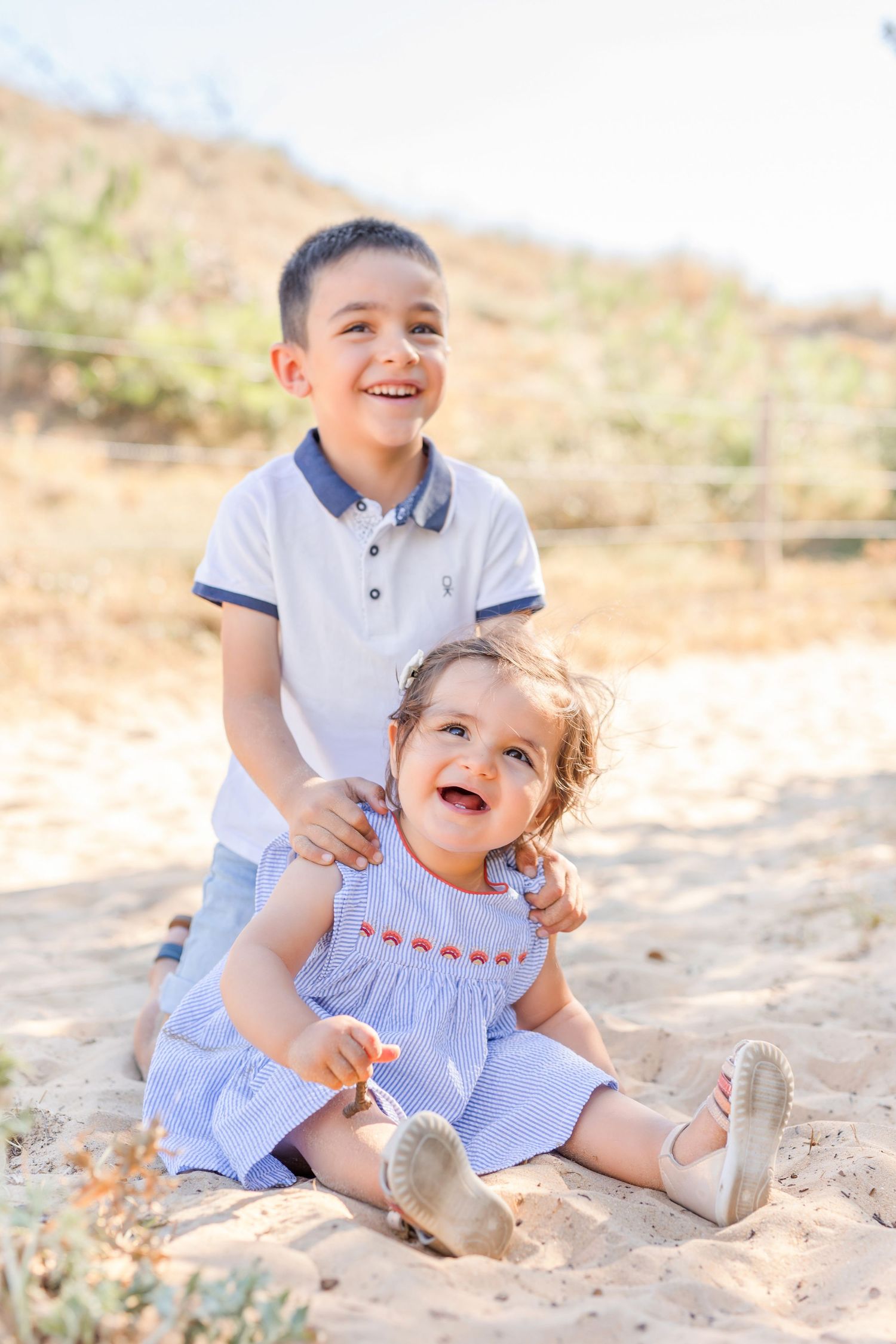 Children laughing and playing in the sand during a beach photo session.