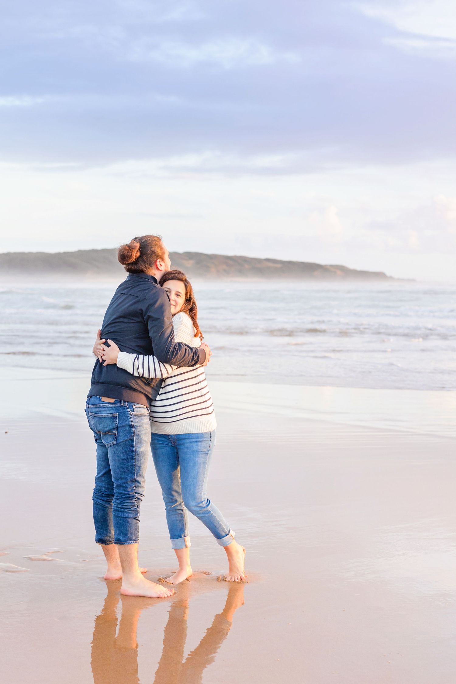 Romantic beach maternity photos with couple sharing intimate moment at sunset.