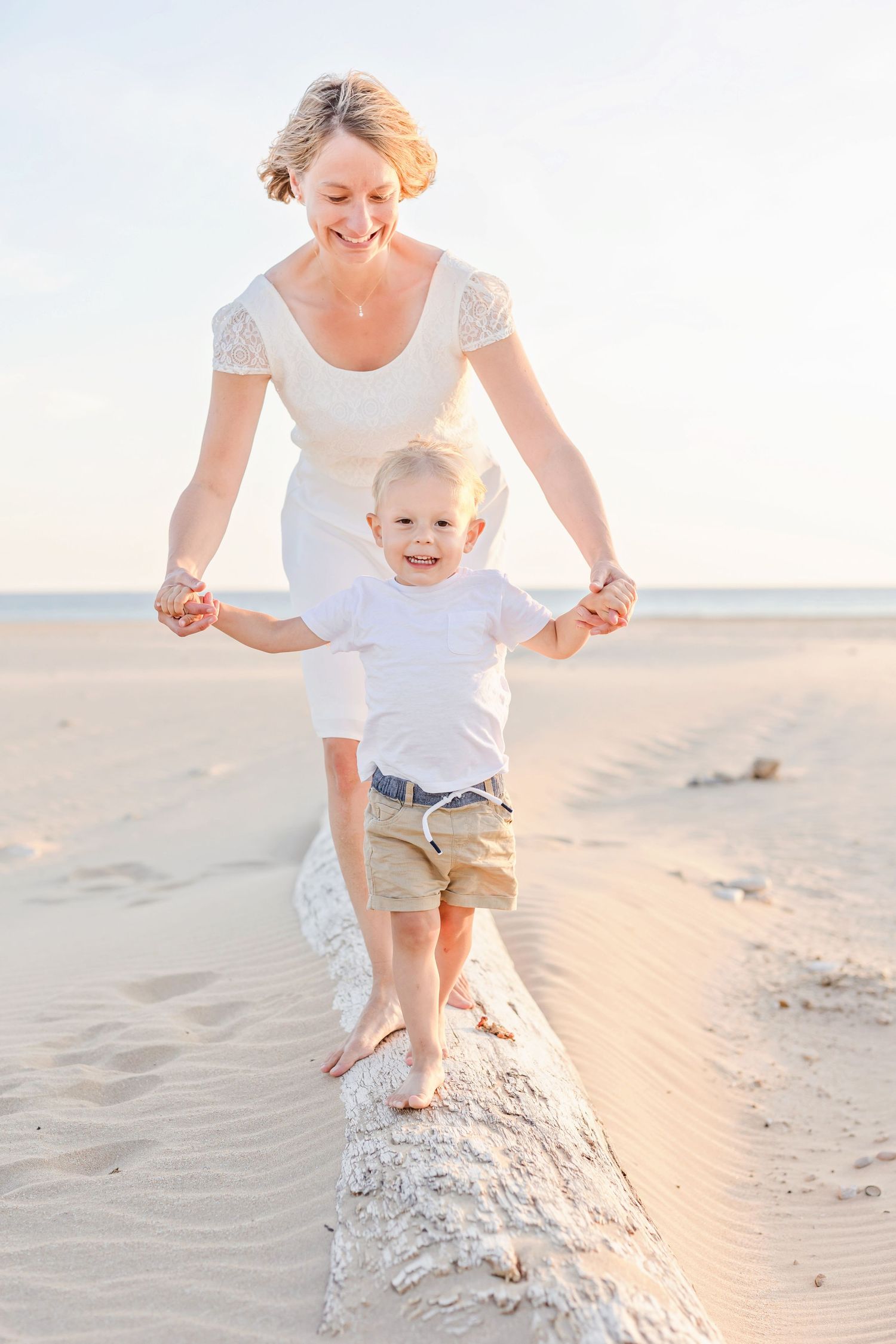 Family members walking and balancing together on a sandy beach ridge during golden hour.