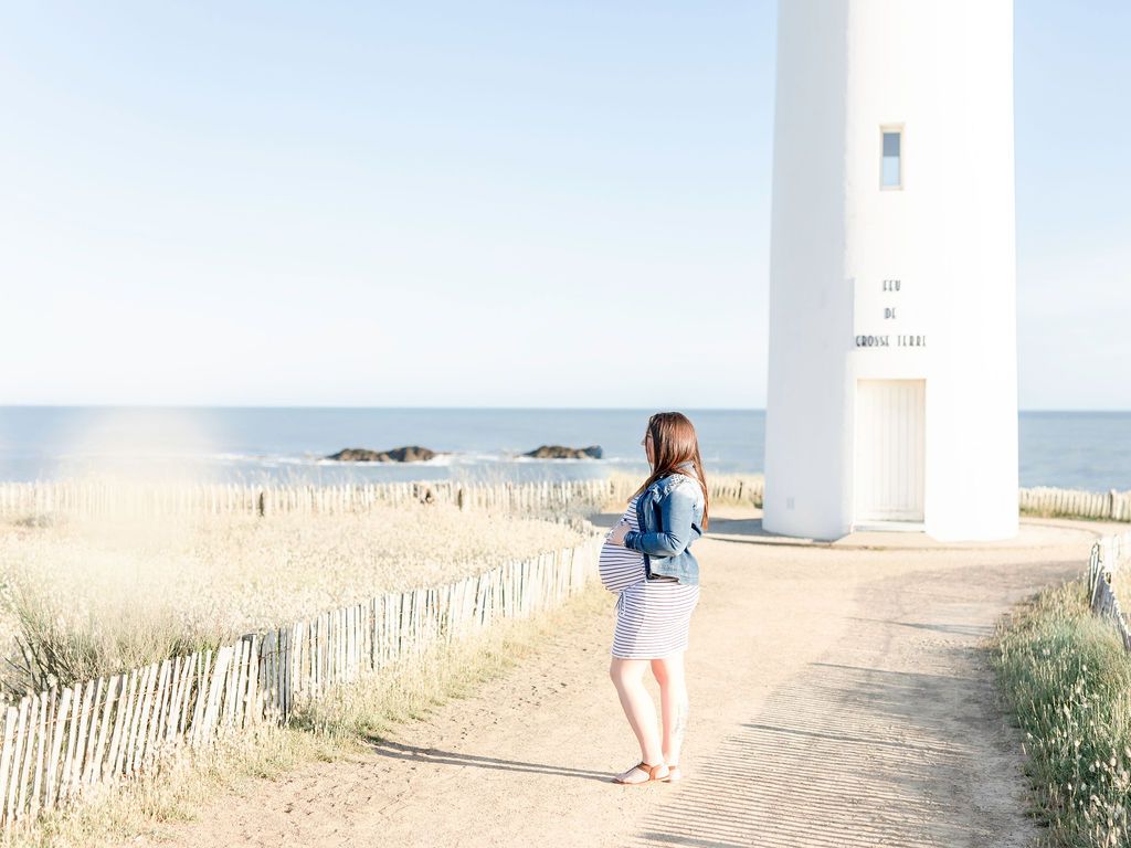 A coastal lighthouse path lined with wooden fences on a sunny day.