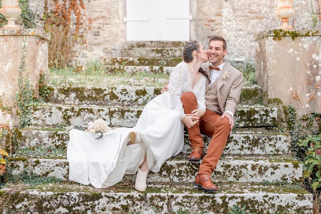 A wedding couple shares an intimate moment on worn stone steps surrounded by autumn foliage.
