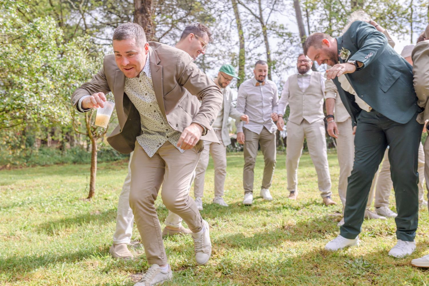 Wedding party members playing games and having fun on a sunny lawn.