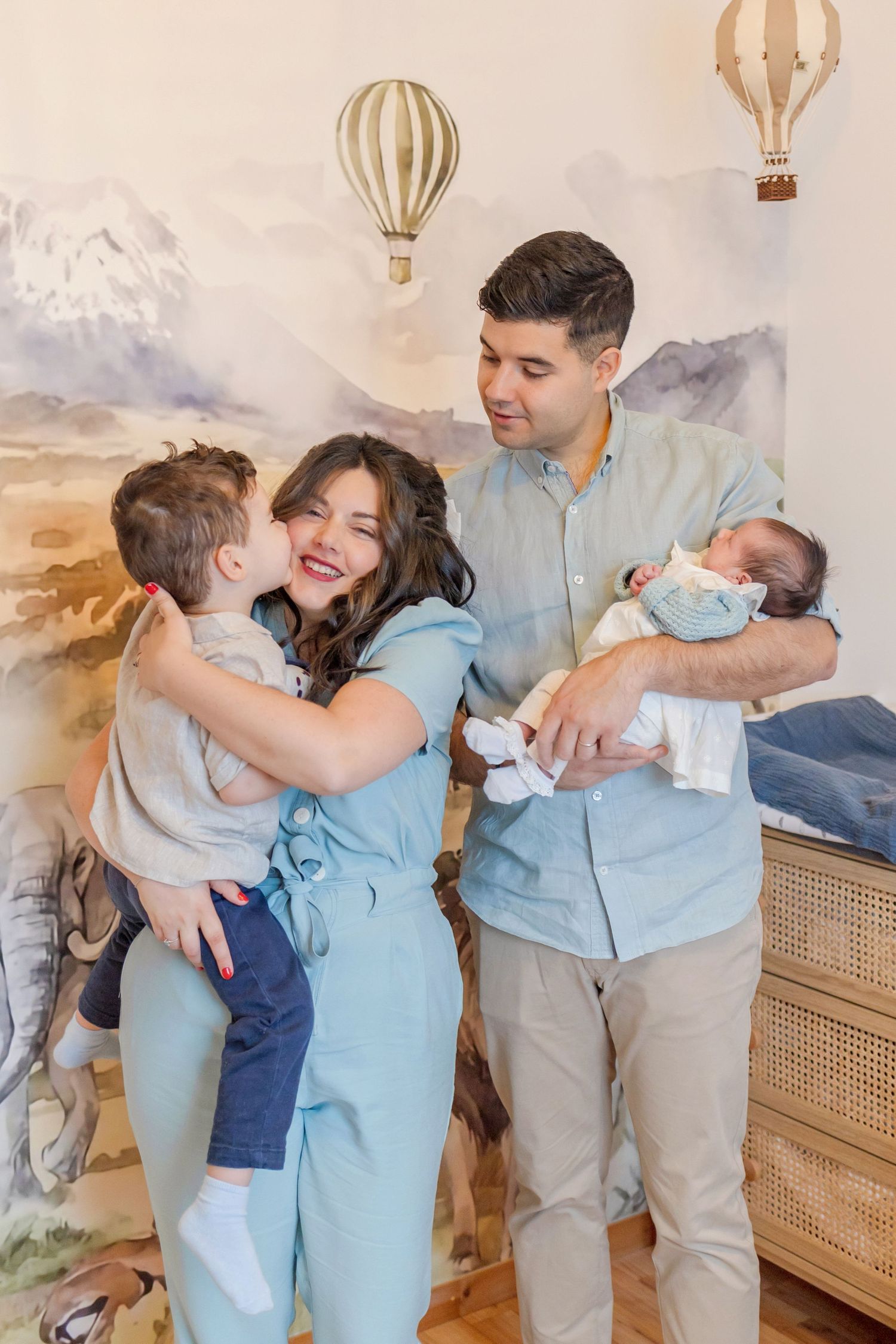 Family moment in nursery decorated with mountain mural and hot air balloon accents.