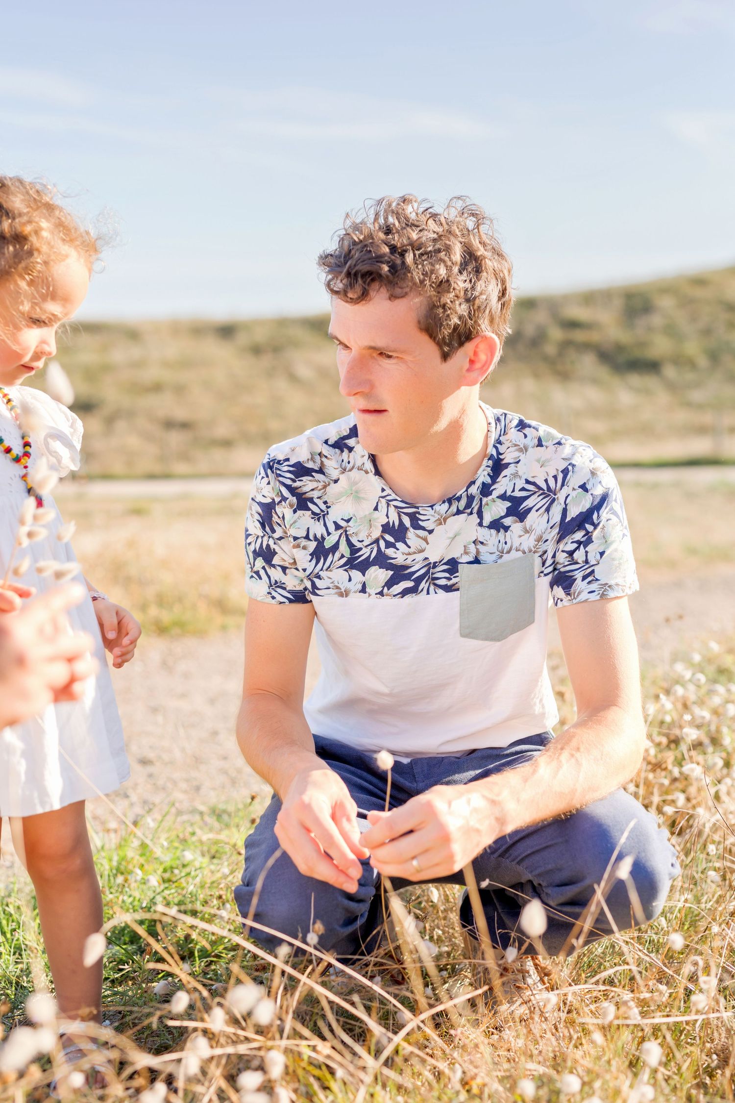 Intimate family moment in field with person wearing blue floral pattern shirt.