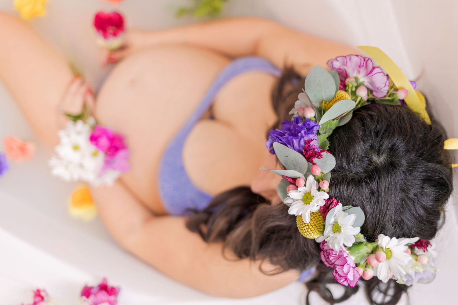 Feminine portrait with scattered colorful blooms and purple attire against white backdrop.