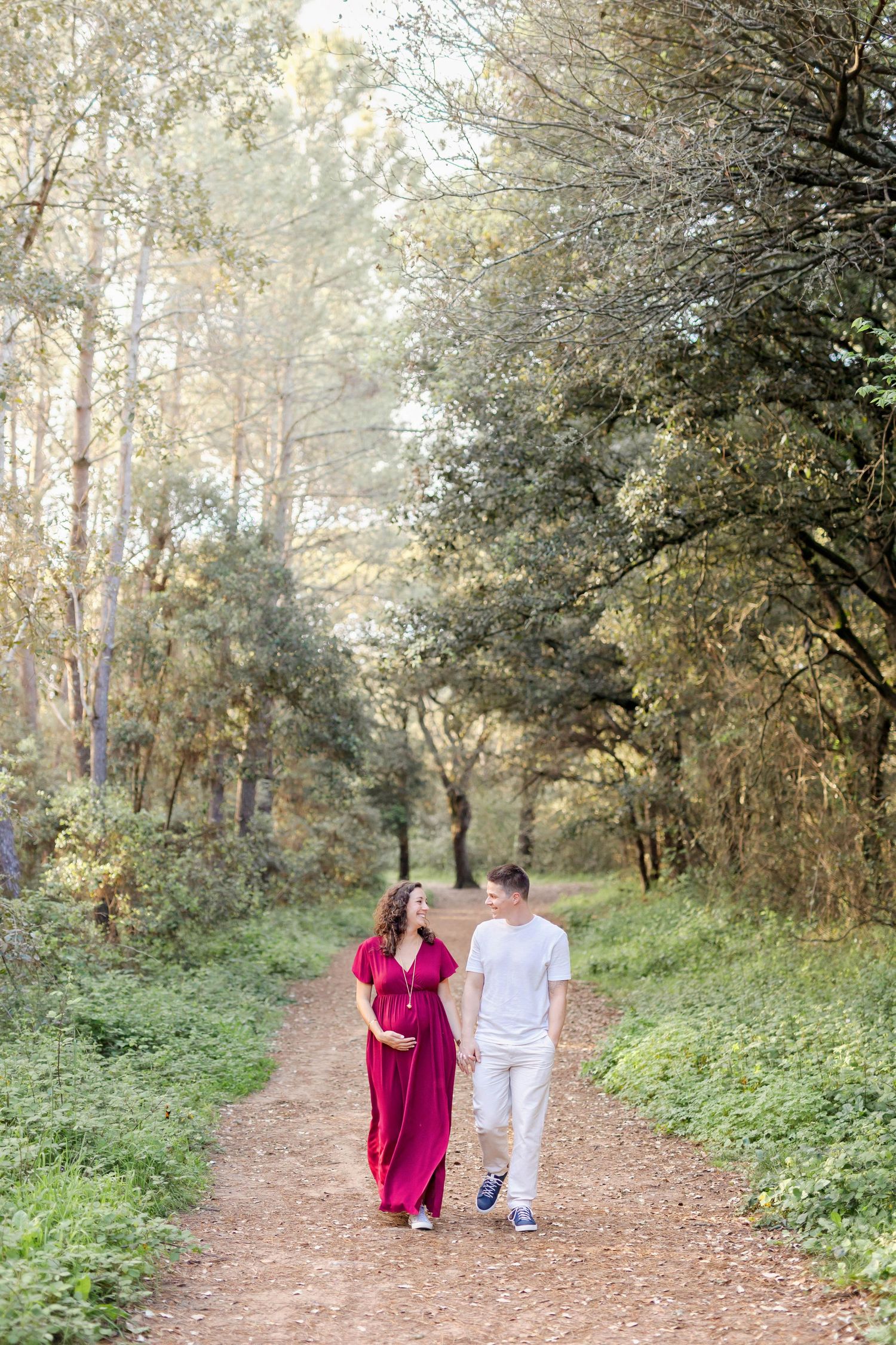 Couple walking hand in hand down a tree-lined autumn path.