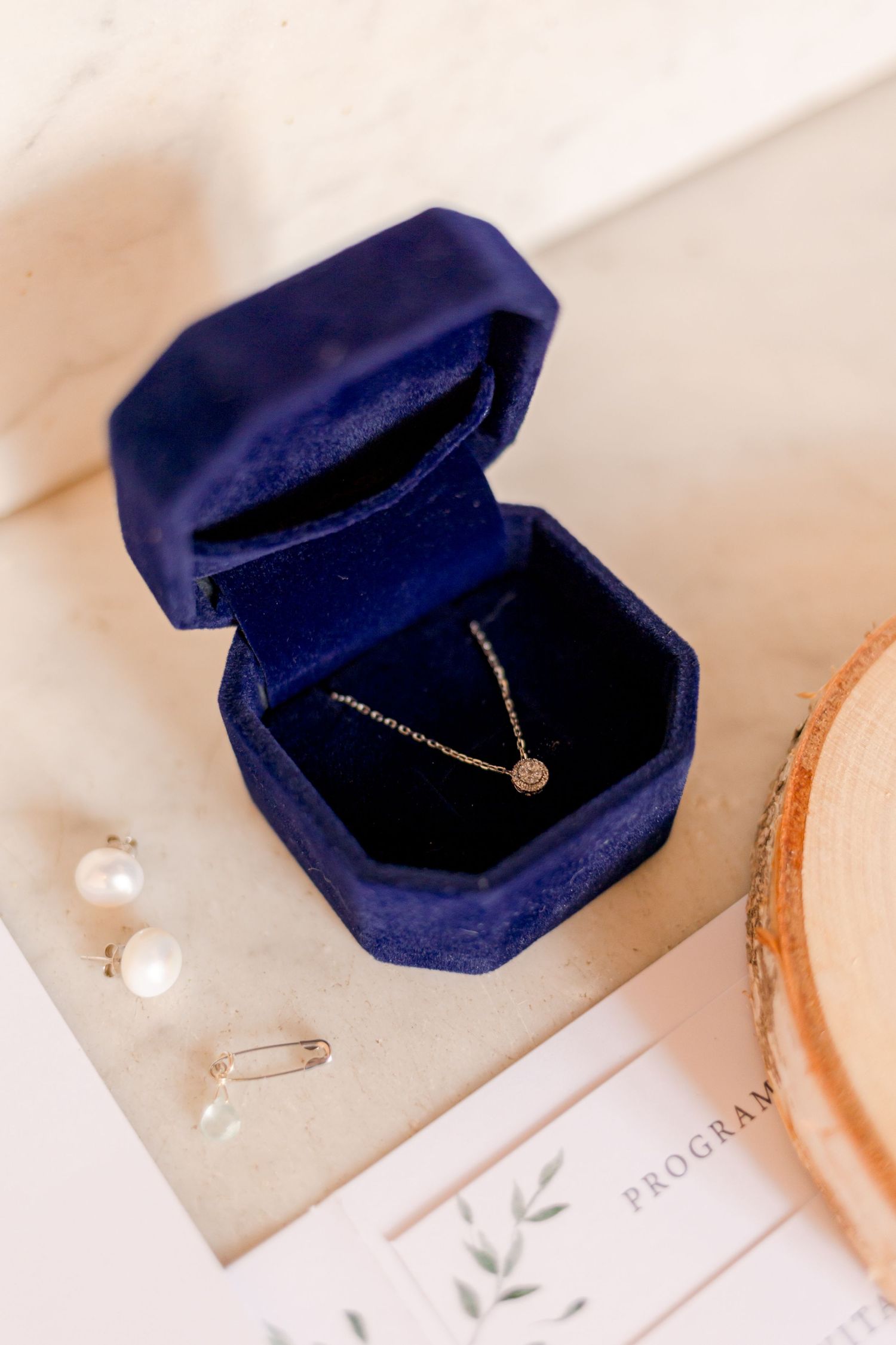 Delicate gold necklace displayed in navy blue velvet jewelry box.