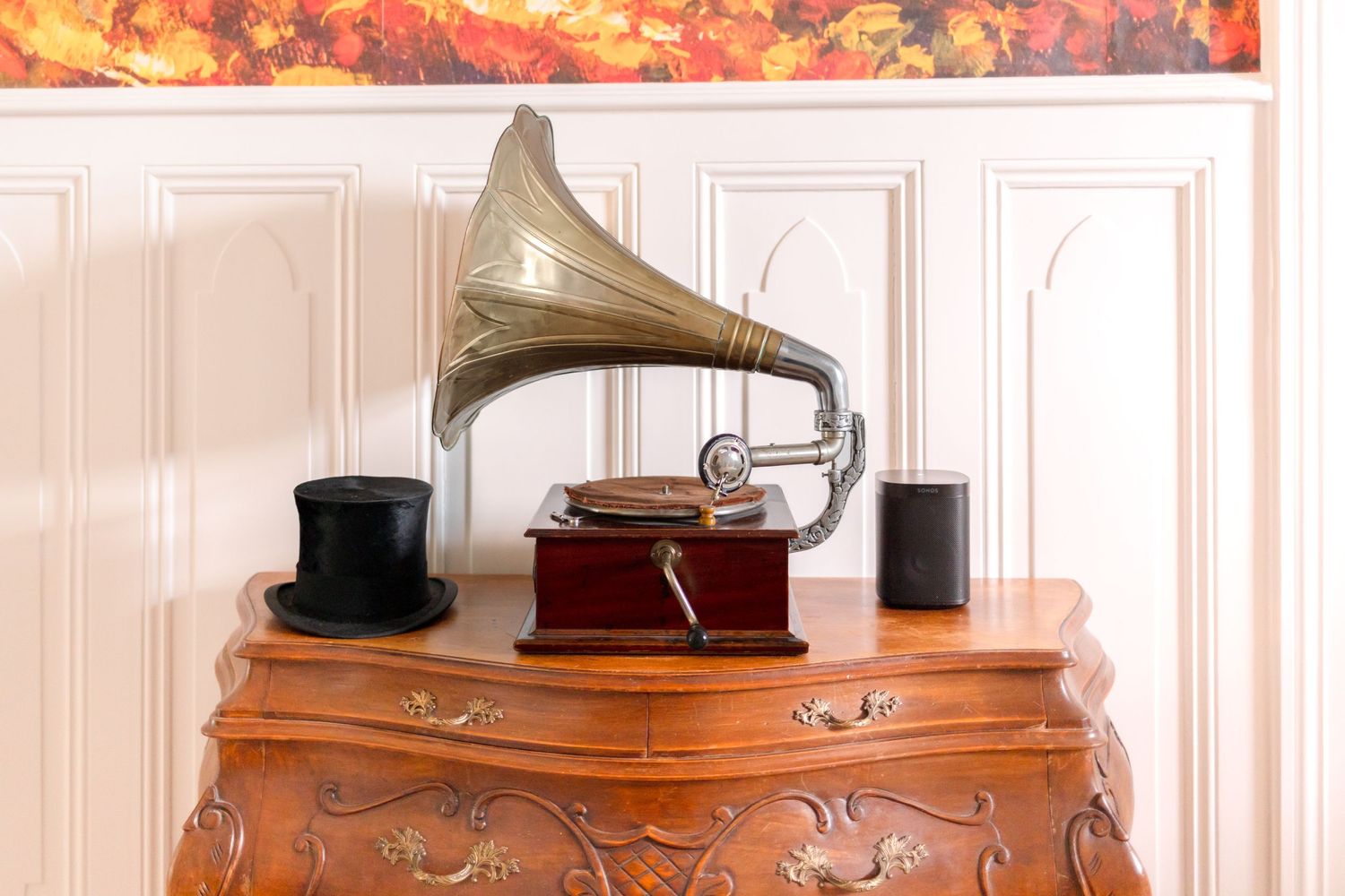 Vintage gramophone with brass horn displayed on an ornate wooden dresser.