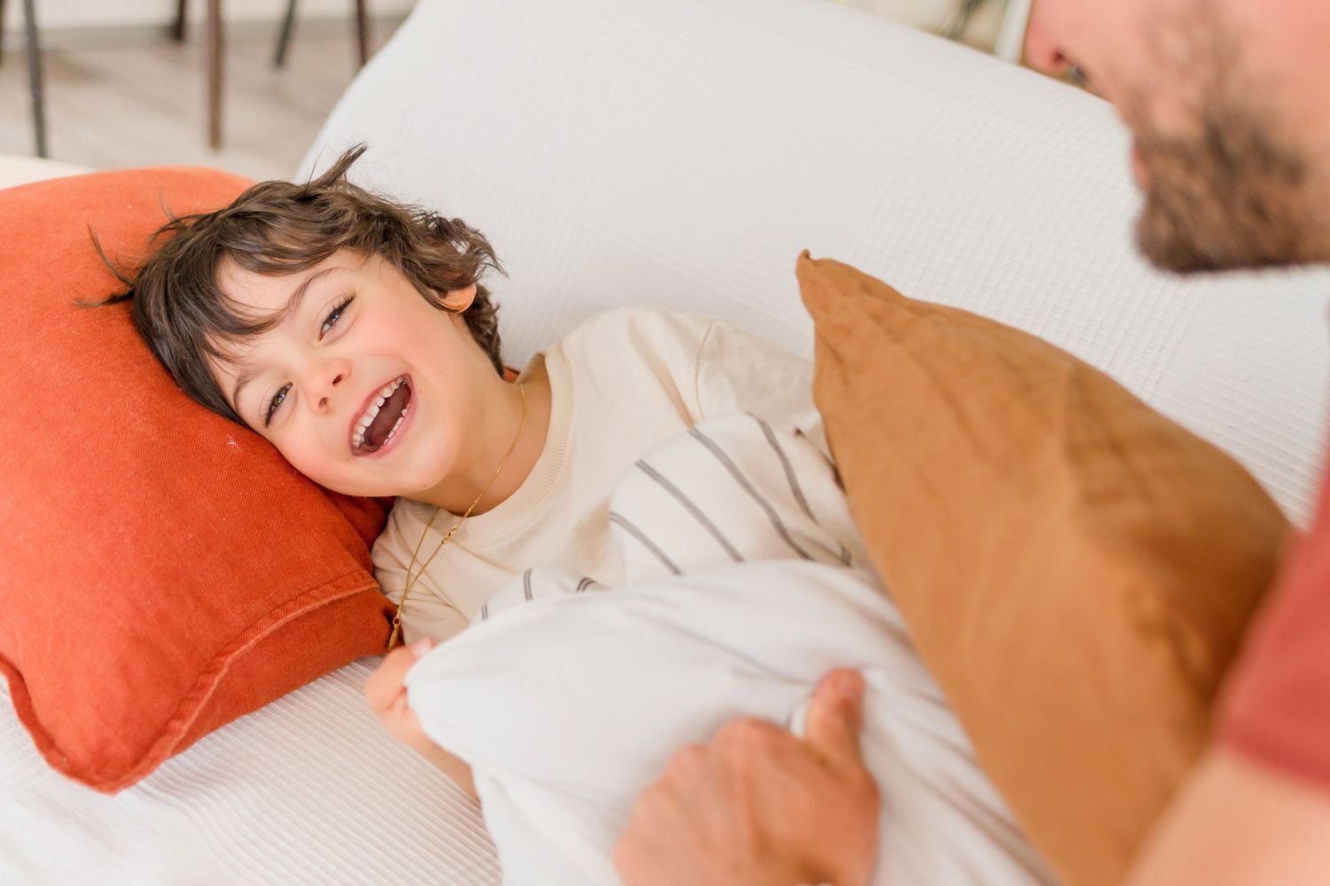 Laughter and movement captured in natural light on white bedding.