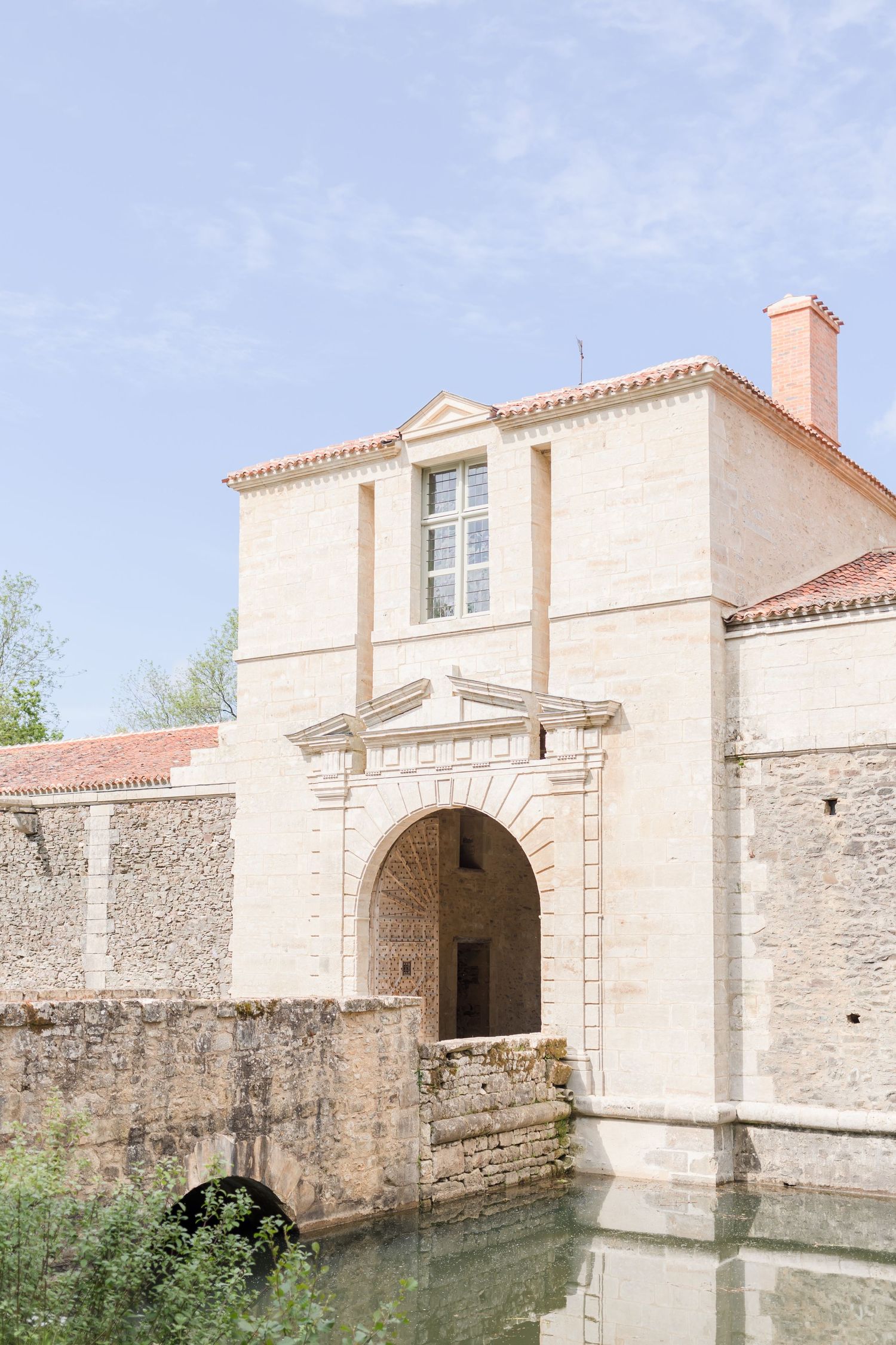 Ancient stone bridge and archway entrance to a cream-colored castle building.
