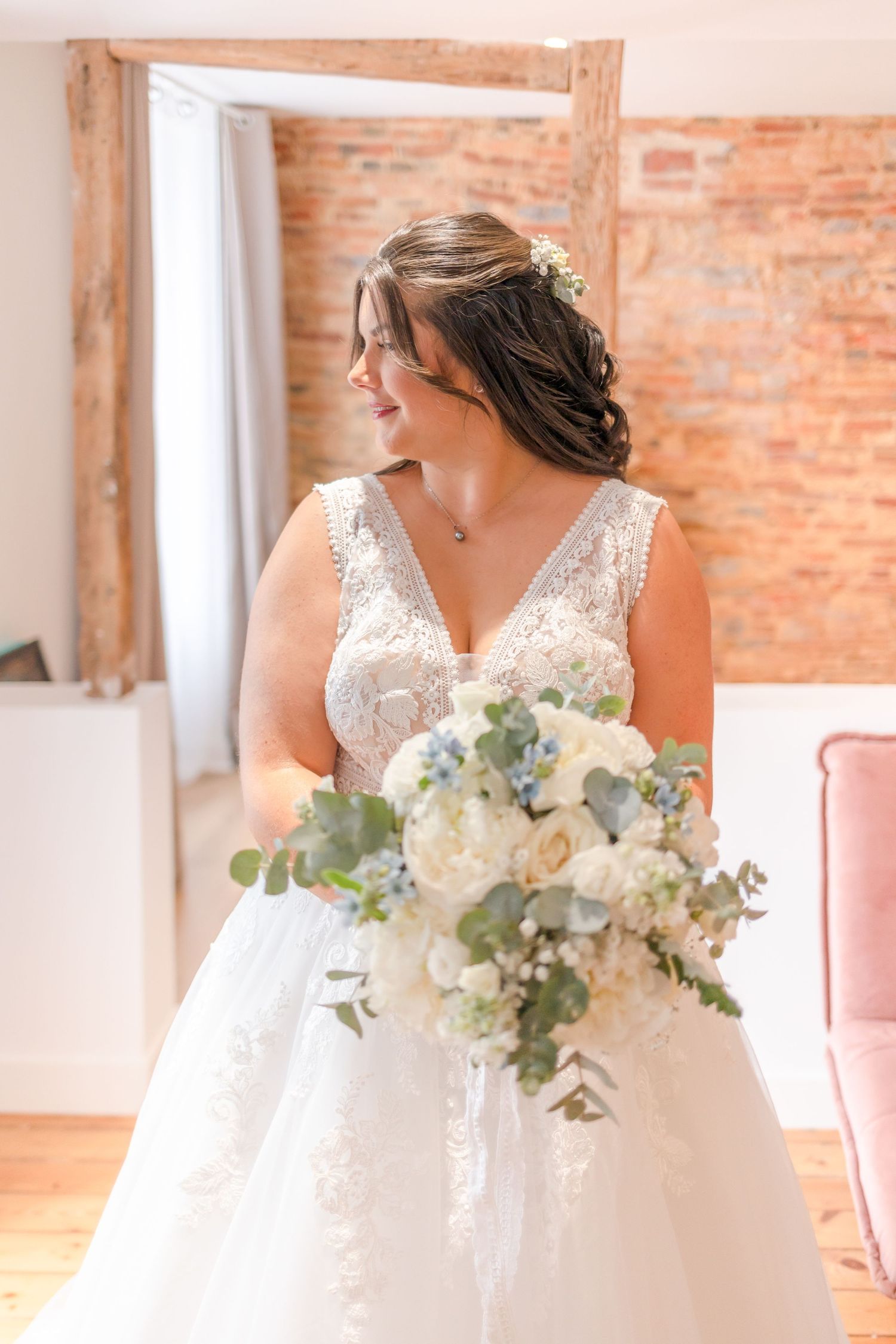 A wedding dress detail shot in a room with exposed brick walls and natural lighting.