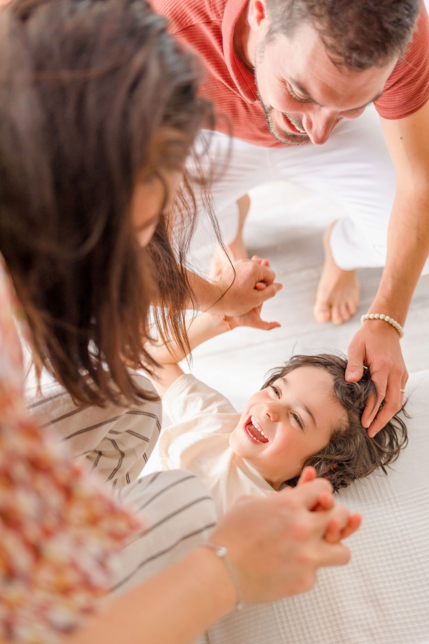 Playful candid moments captured on a white couch with warm lighting.