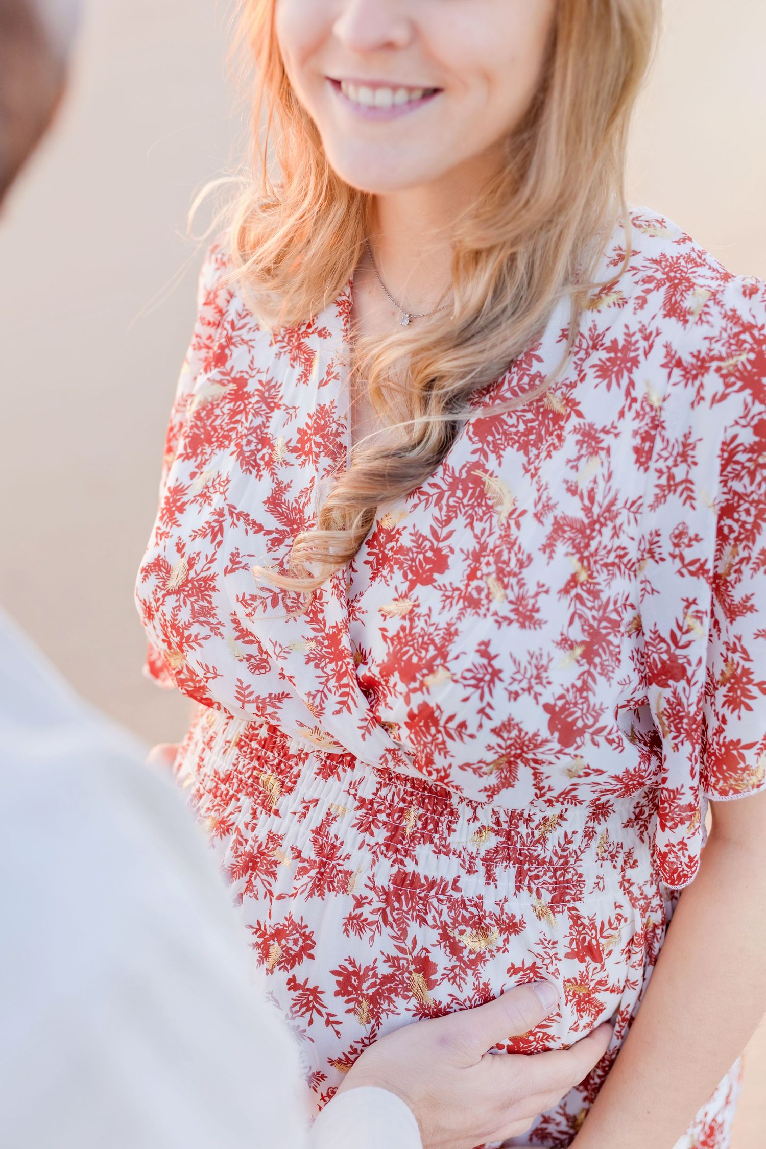 A close-up portrait showing a floral dress detail with warm sunset lighting.