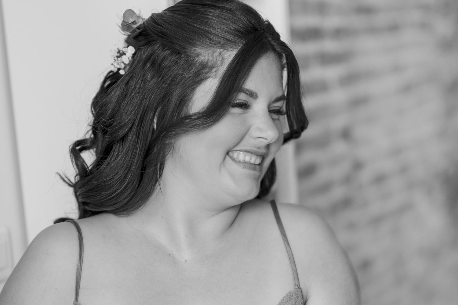 A black and white portrait showing a joyful expression and styled dark hair.