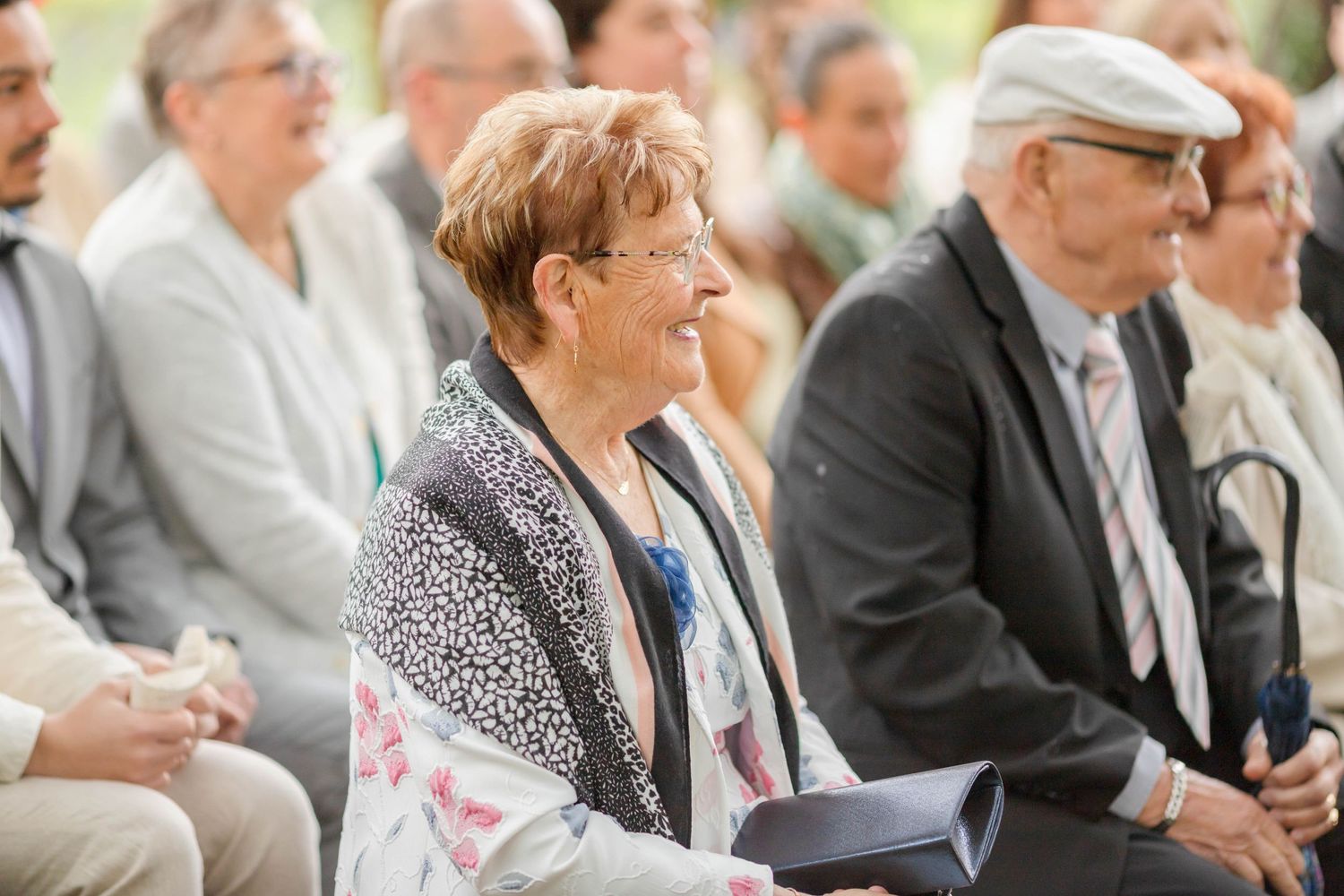 Attendees seated in rows at an outdoor event with natural forest backdrop.