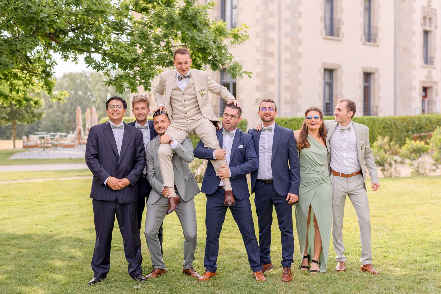 Groomsmen strike entertaining poses for group photos on castle grounds.