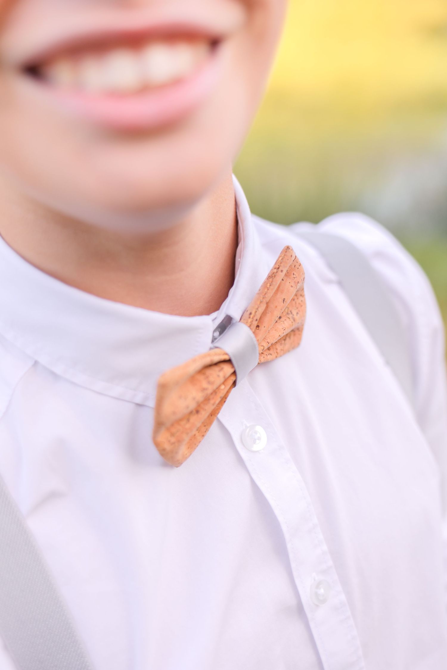 Close up of peach colored bow tie against white collar.