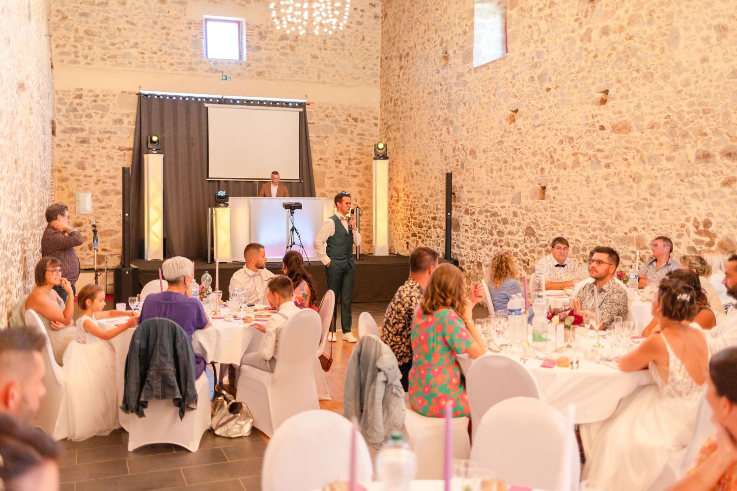 Wedding reception venue with stone walls and white chairs as guests gather for the celebration.