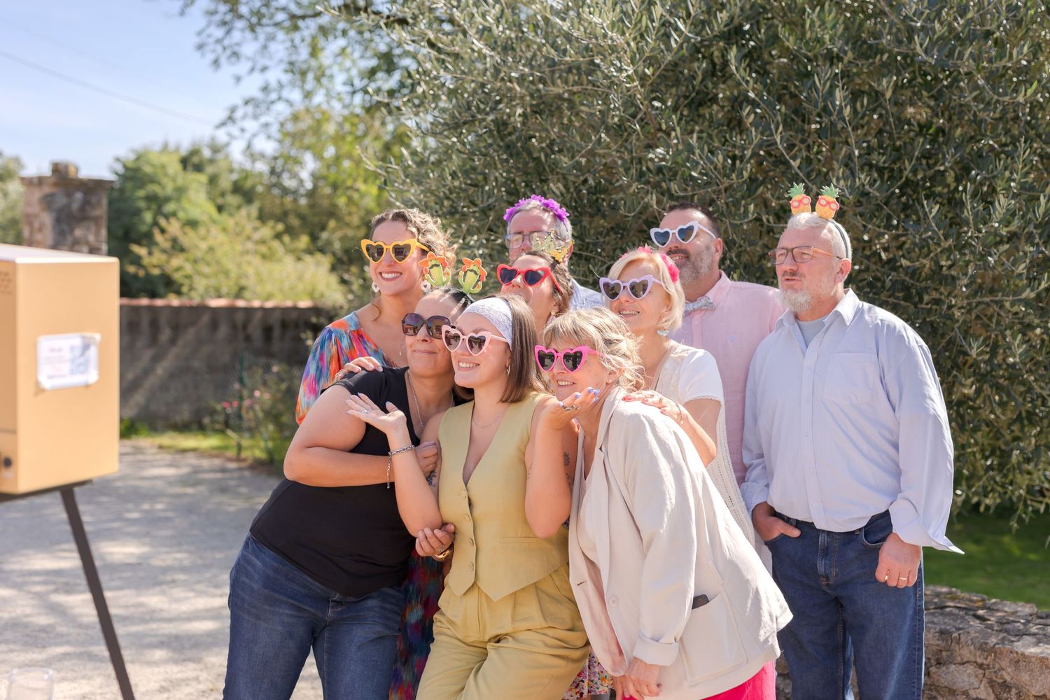 Group of wedding guests posing together outdoors wearing sunglasses and casual attire.