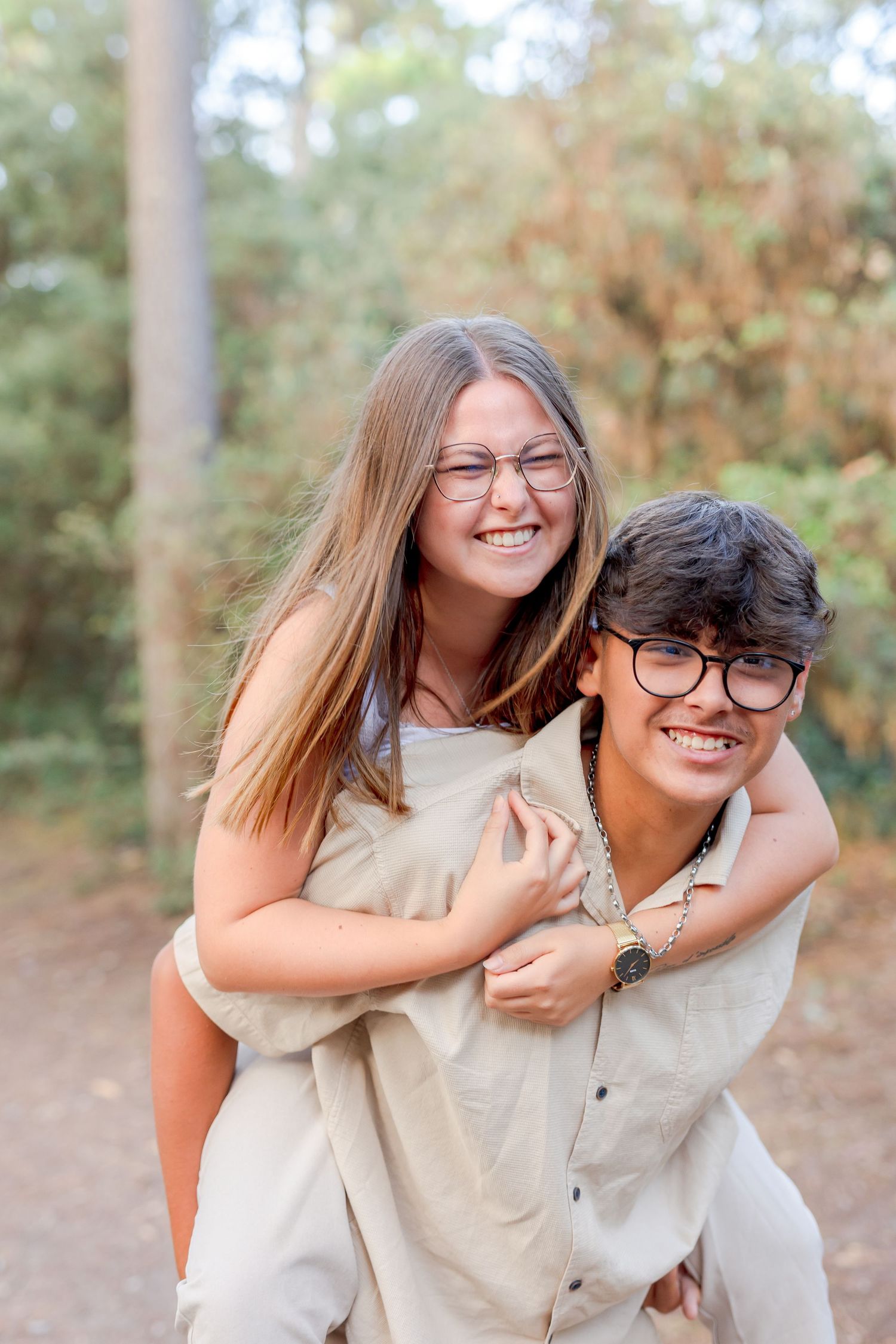 A playful piggyback ride moment captured in golden sunlight on a forest trail.