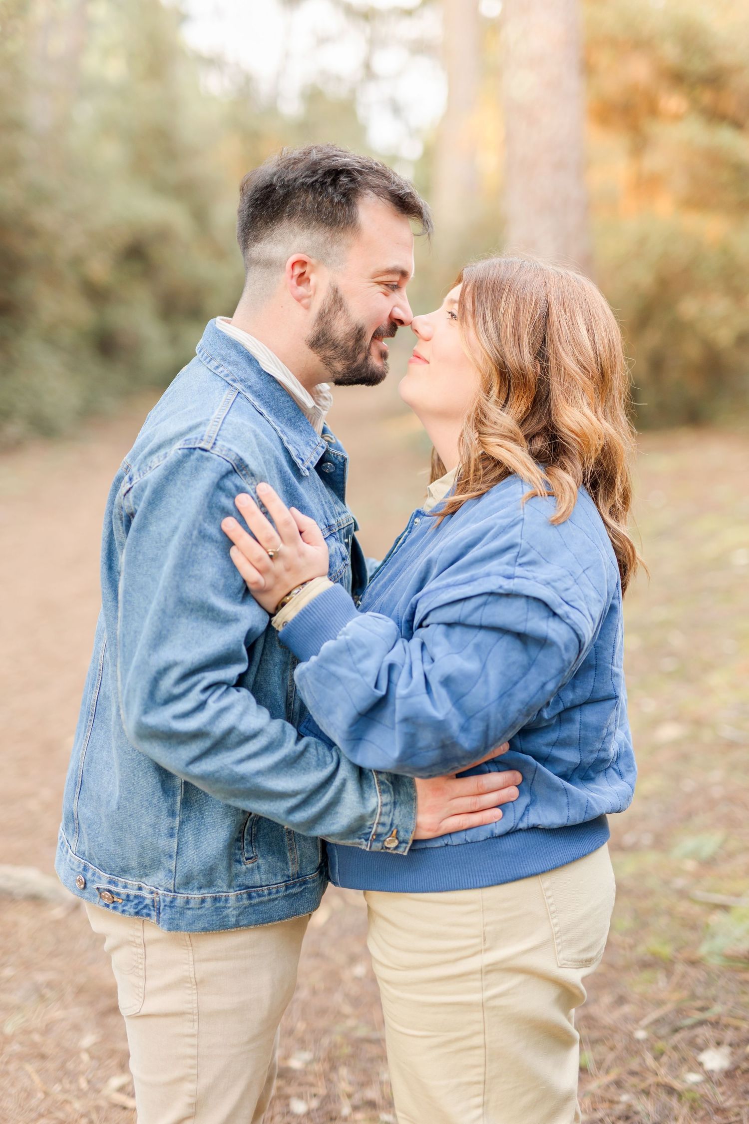 Romantic couple in denim jackets sharing intimate moment outdoors during golden hour.