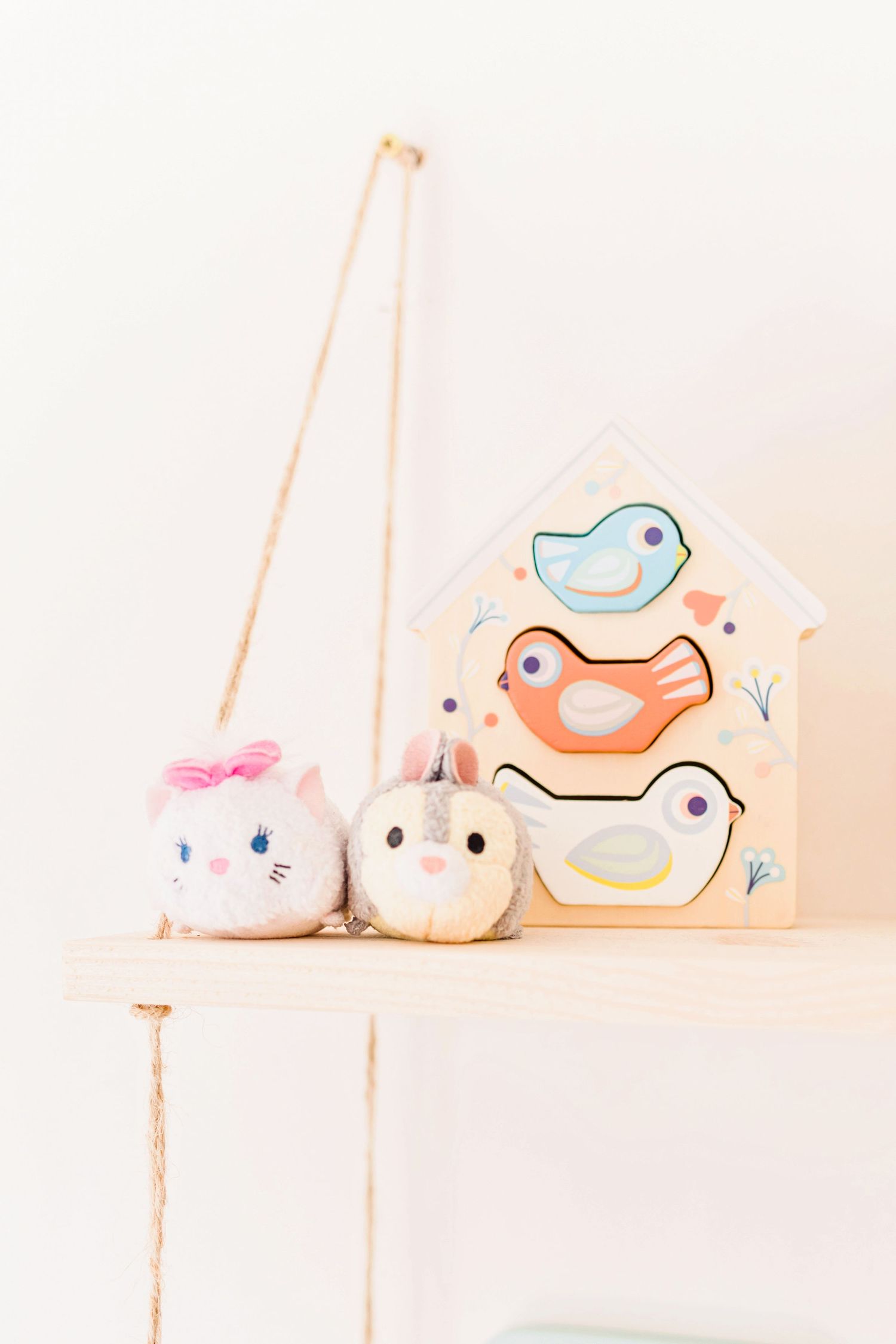 Soft pastel decorative bird ornaments arranged on a white shelf with delicate details.