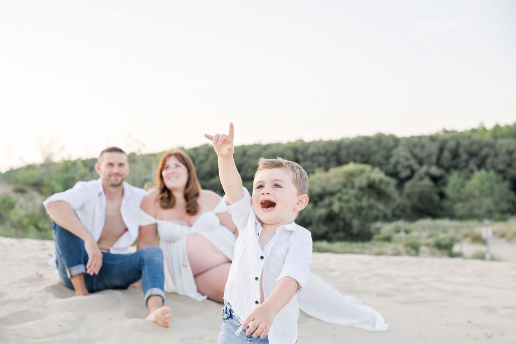 Happy family enjoying playful moments together on sandy beach at sunset.