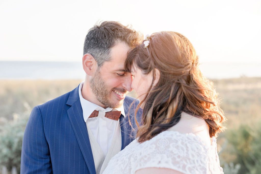 A romantic beach wedding couple shares an intimate moment against a coastal backdrop.