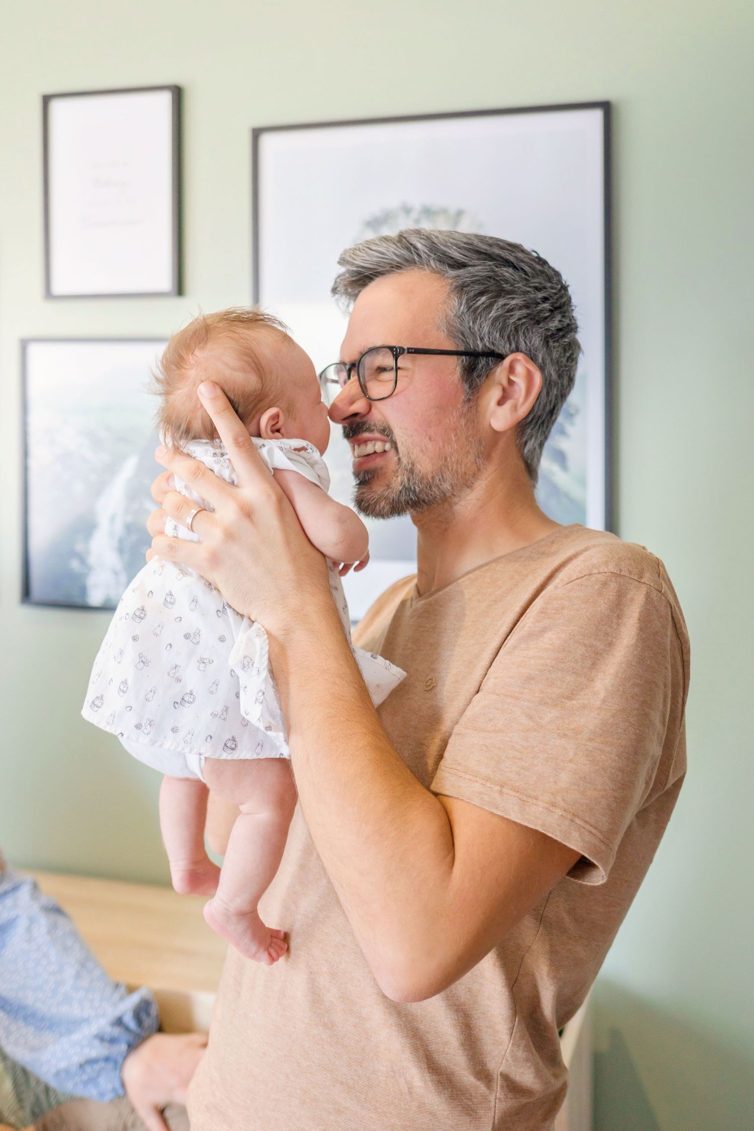 Happy moment between parent and baby in living room with framed artwork.