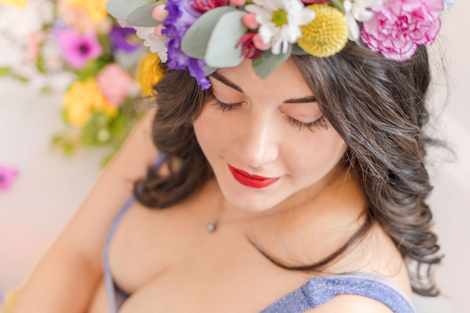Dreamy close-up portrait with floral crown and red lipstick.