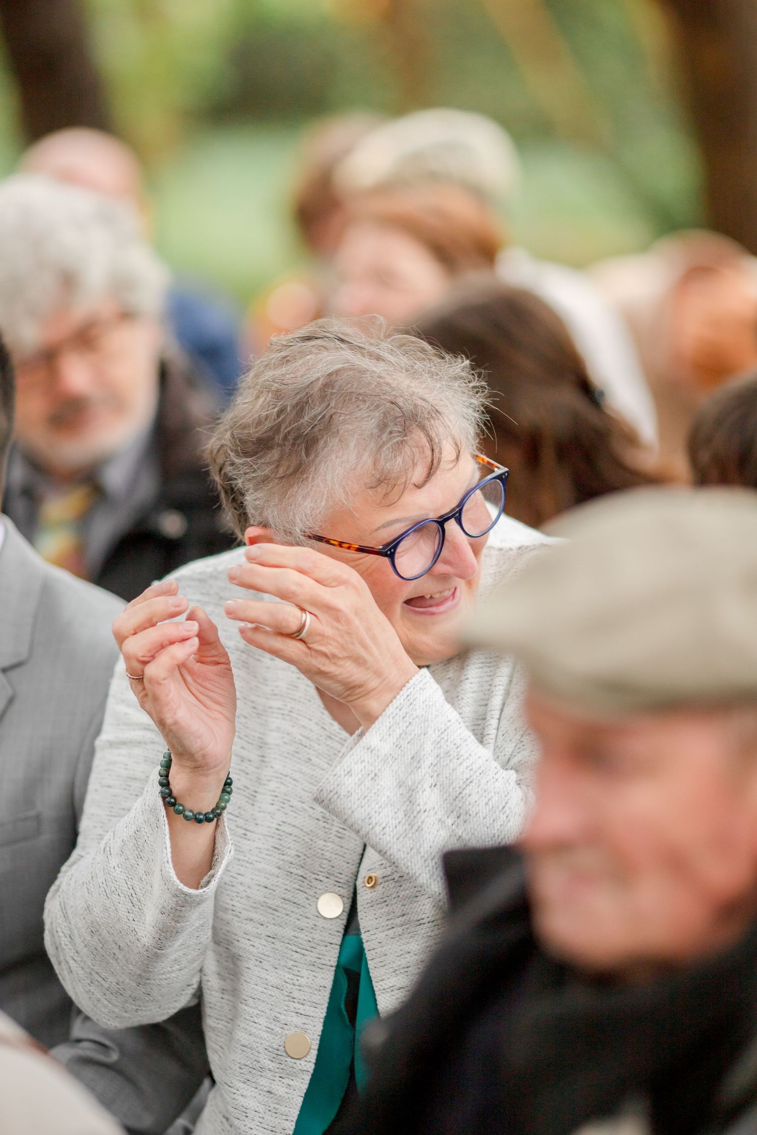 Emotional guest wipes tears while watching forest wedding ceremony.