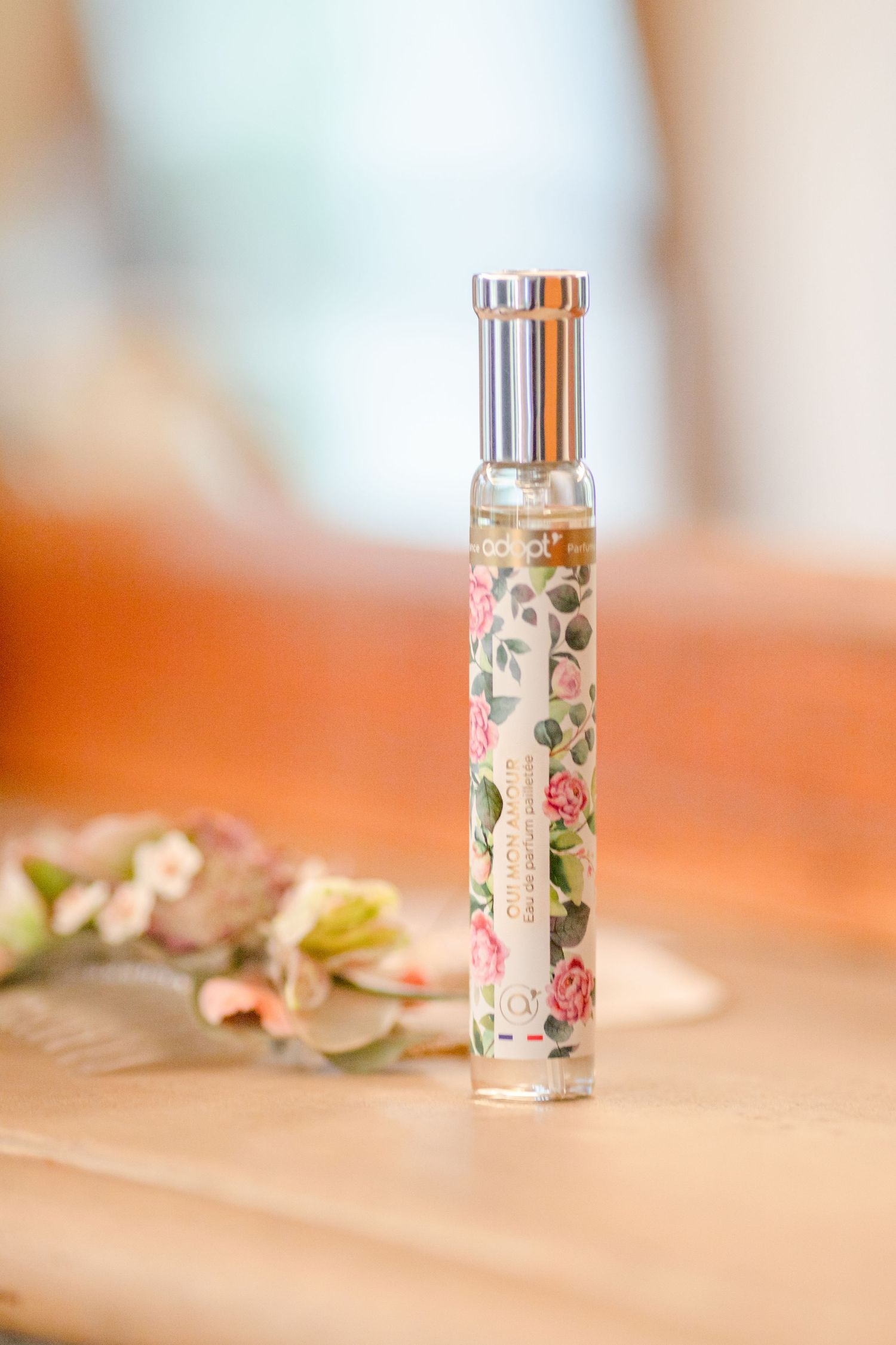 Decorative floral perfume bottle with metallic cap on blurred background.