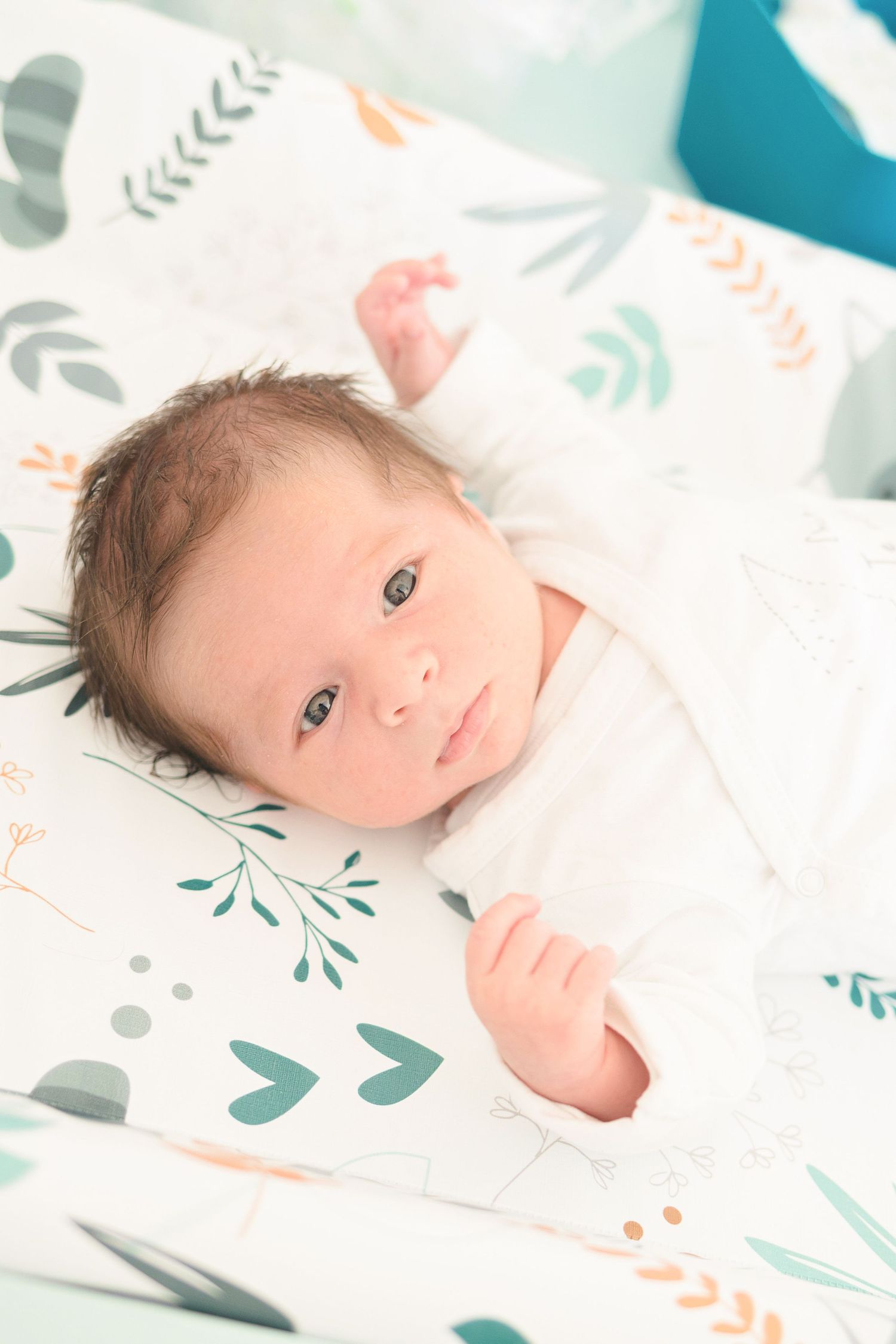 Close up of baby on patterned blanket with botanical and heart designs.