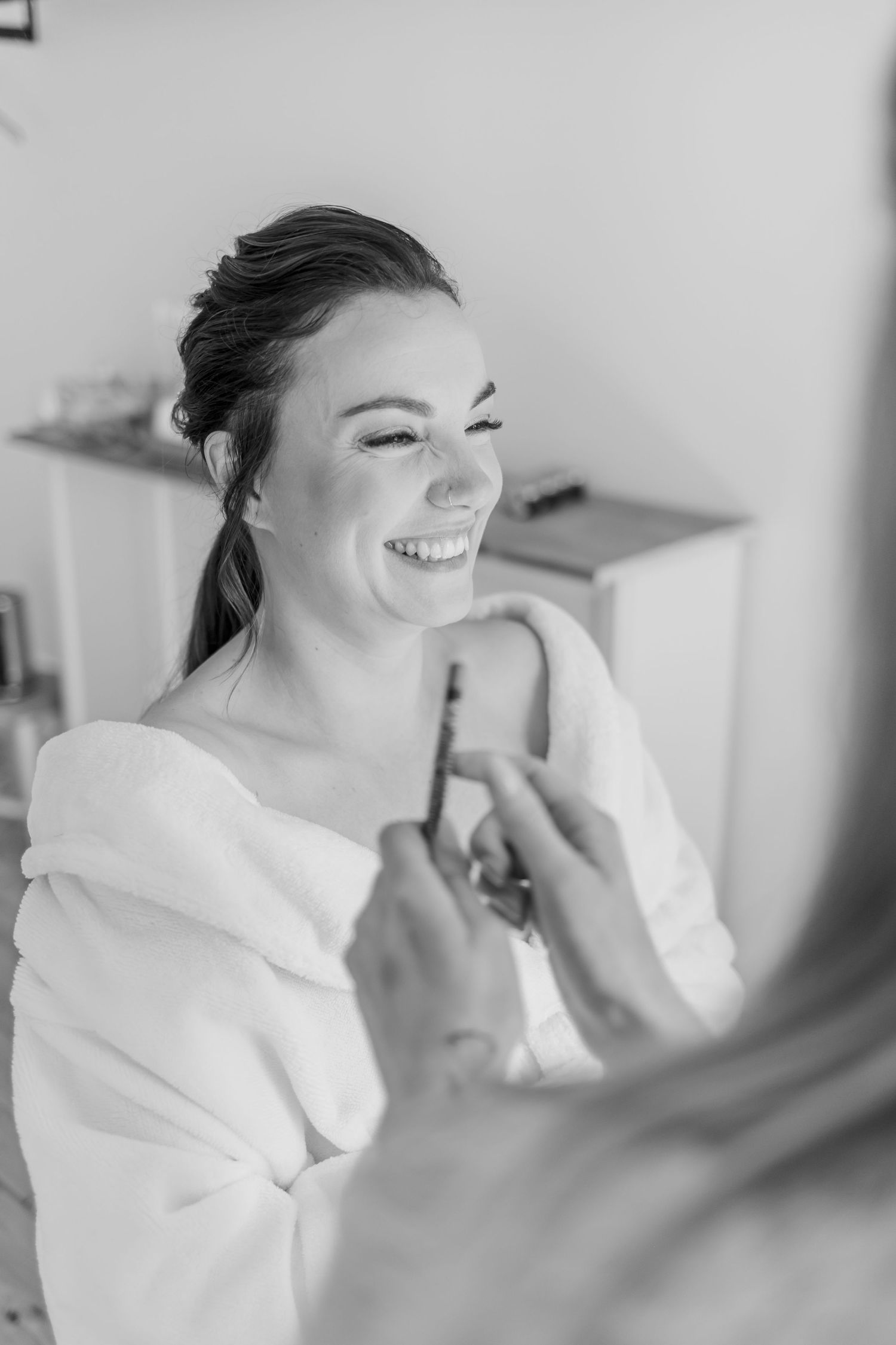Black and white image showing joyful expression during wedding day preparations.