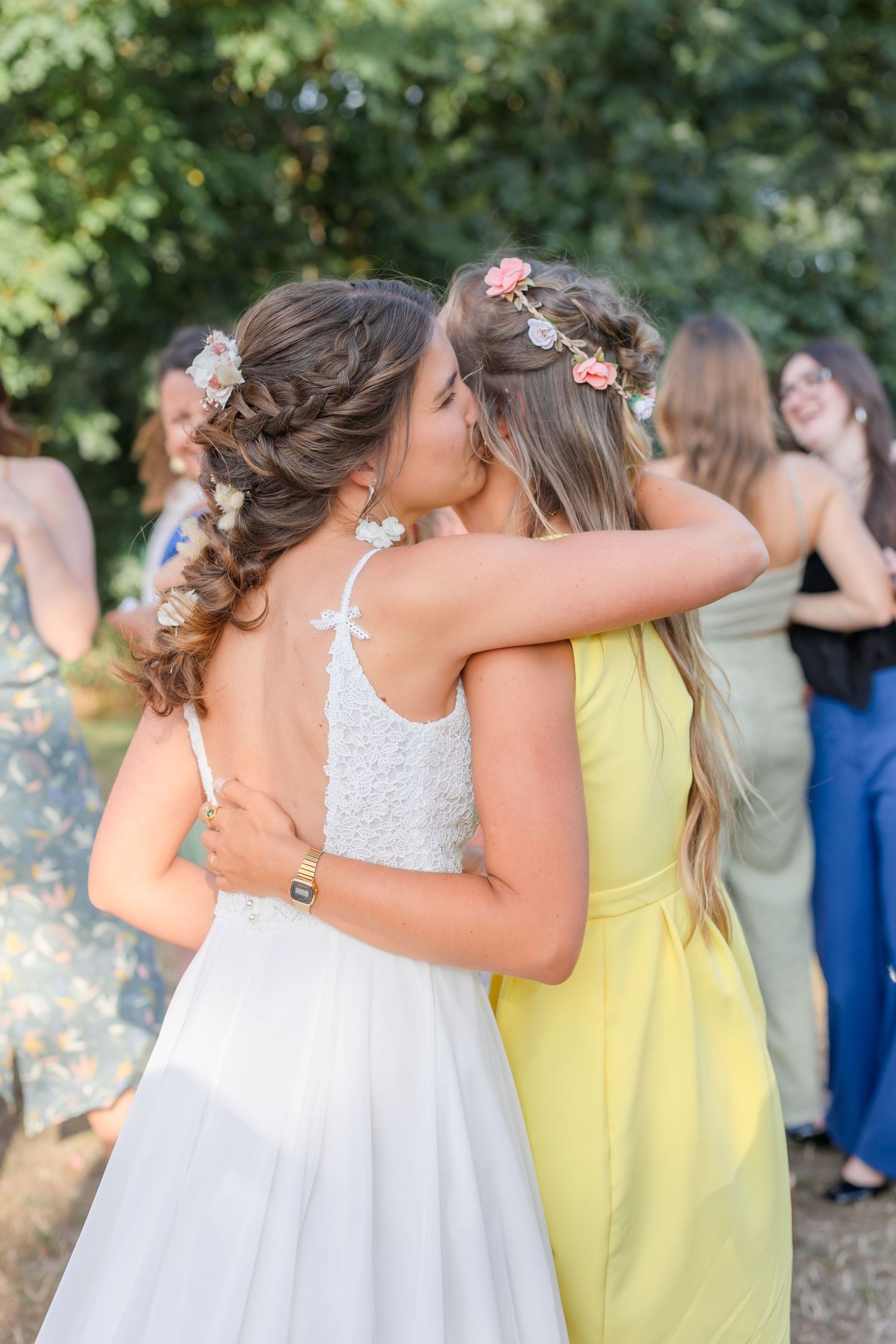 Wedding celebration captures emotional embraces between attendees in pastel dresses.