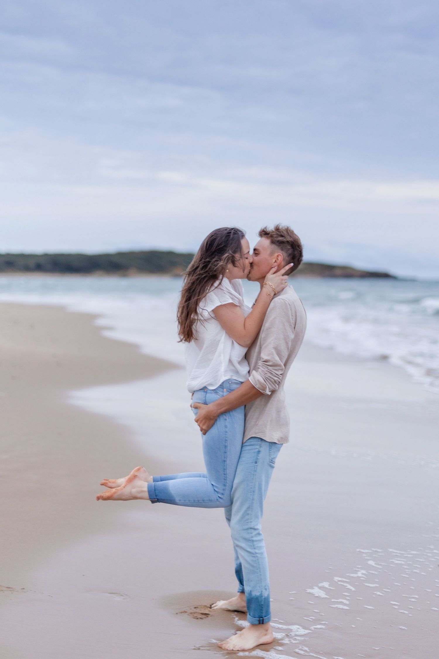 A romantic beach moment with waves crashing on the shore in the background.